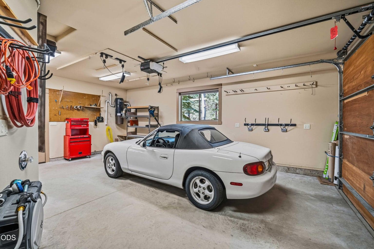 The additional garage bay functions as a highly usable workshop and vehicle space, with overhead storage systems, tool organization, windows and direct access to the utility room.