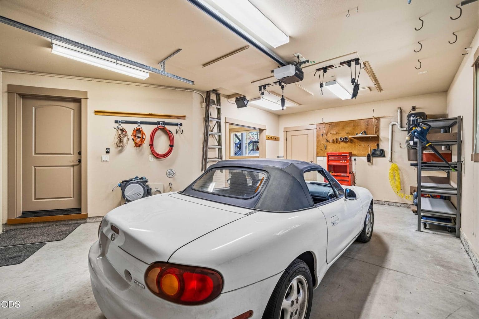 Built-in organization, ceiling-mounted storage, utility connections and a dedicated work zone make this garage area especially useful for projects, recreation equipment and vehicle care.