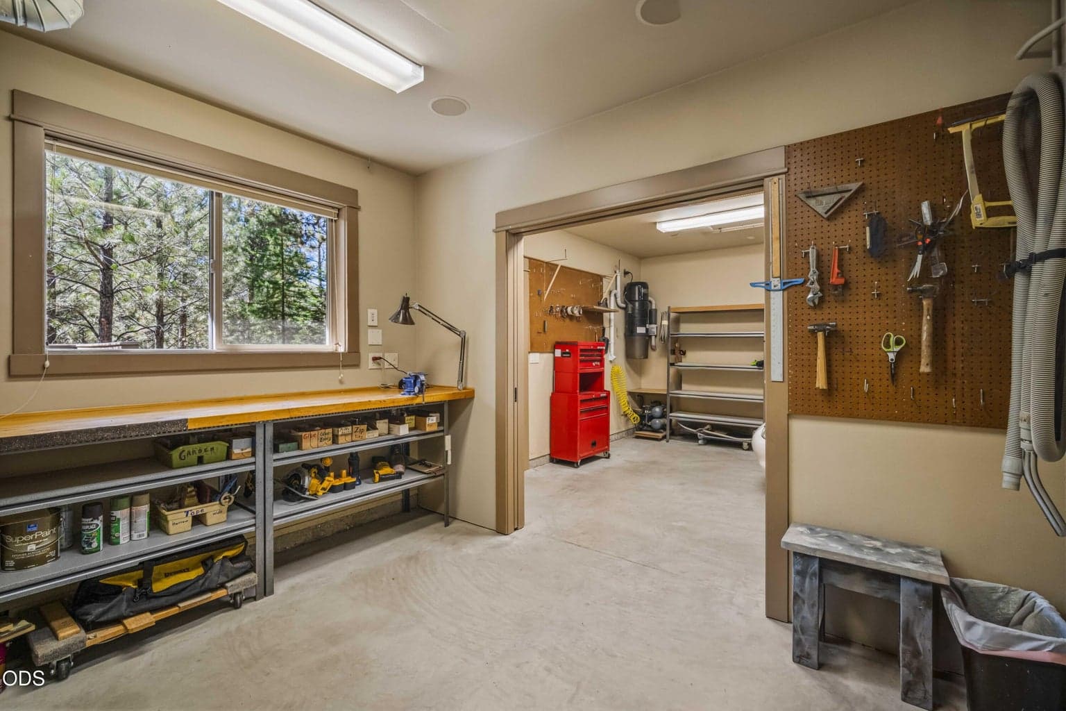 Open shelving, a pegboard tool wall and broad workbench provide organized space for woodworking, repairs, gardening equipment and year-round home projects.