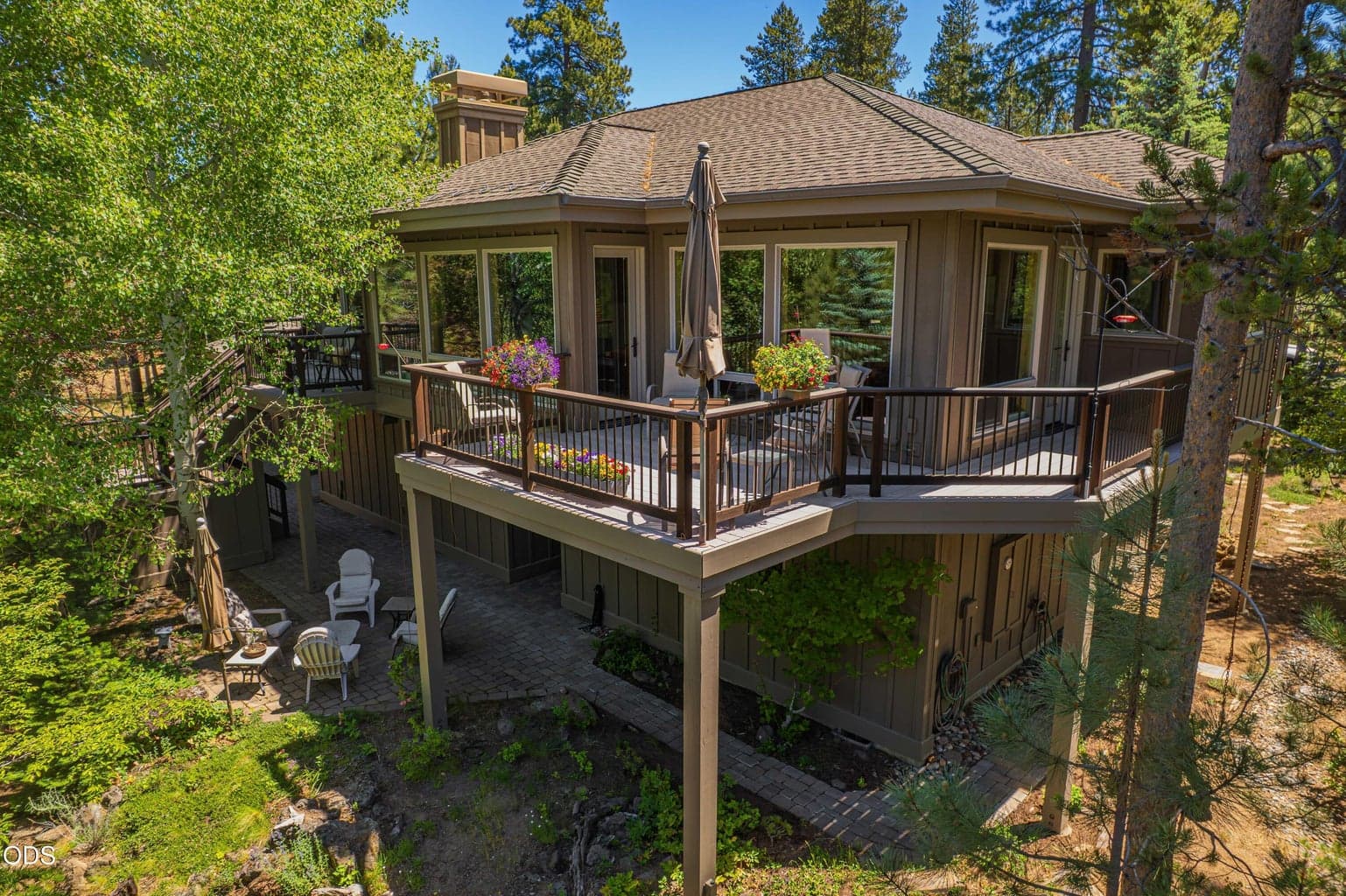 This rear exterior view reveals the home’s layered outdoor living spaces, including the wraparound deck serving the dining and kitchen areas, the separate deck adjoining the primary suite, lower patios and connecting exterior stairs. Surrounded by mature trees, the architecture is carefully integrated into the extraordinary Sunriver forest setting.