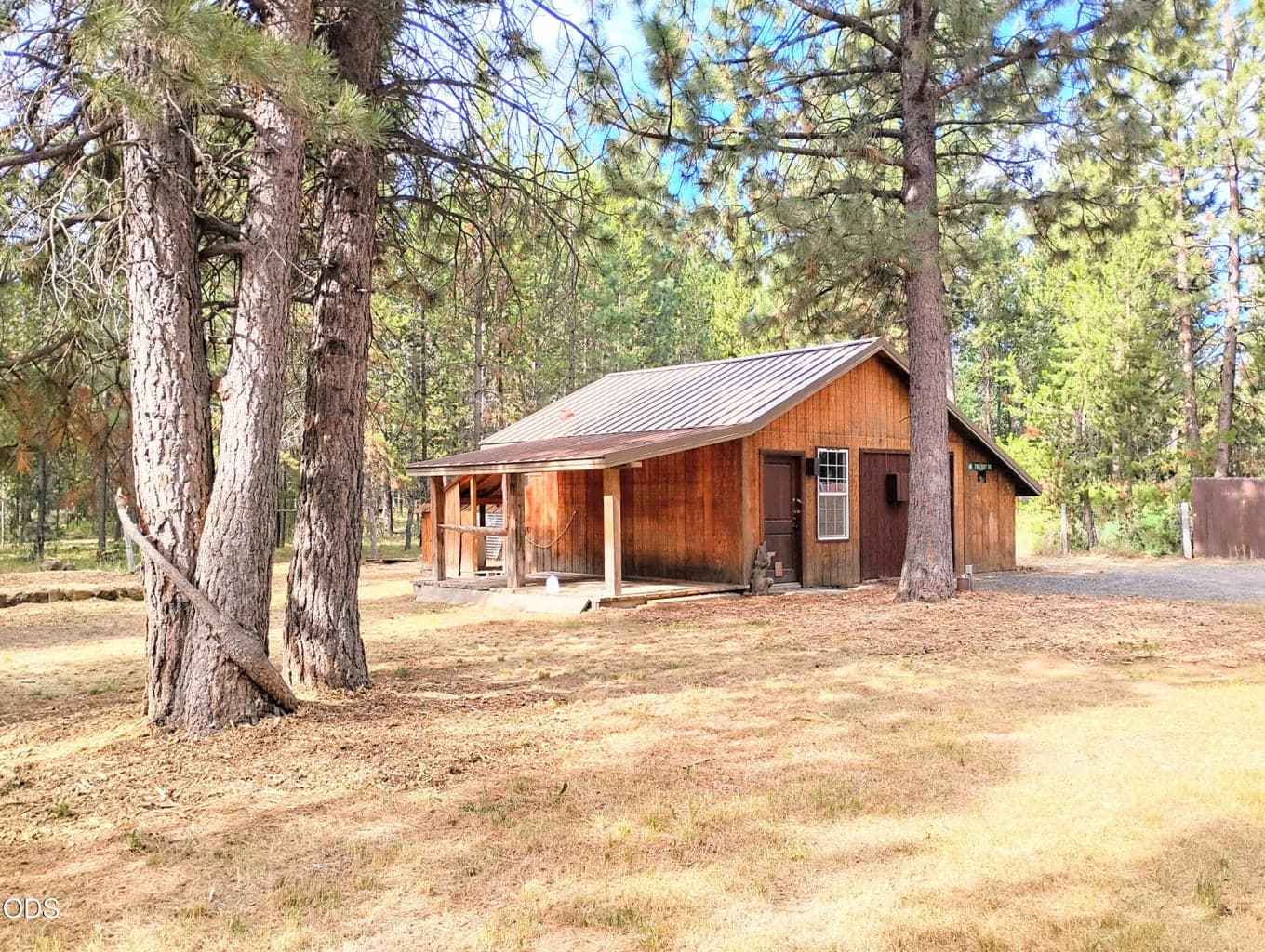 Alternate view of the shop and covered porch, highlighting the wooded surroundings and usable outdoor space.