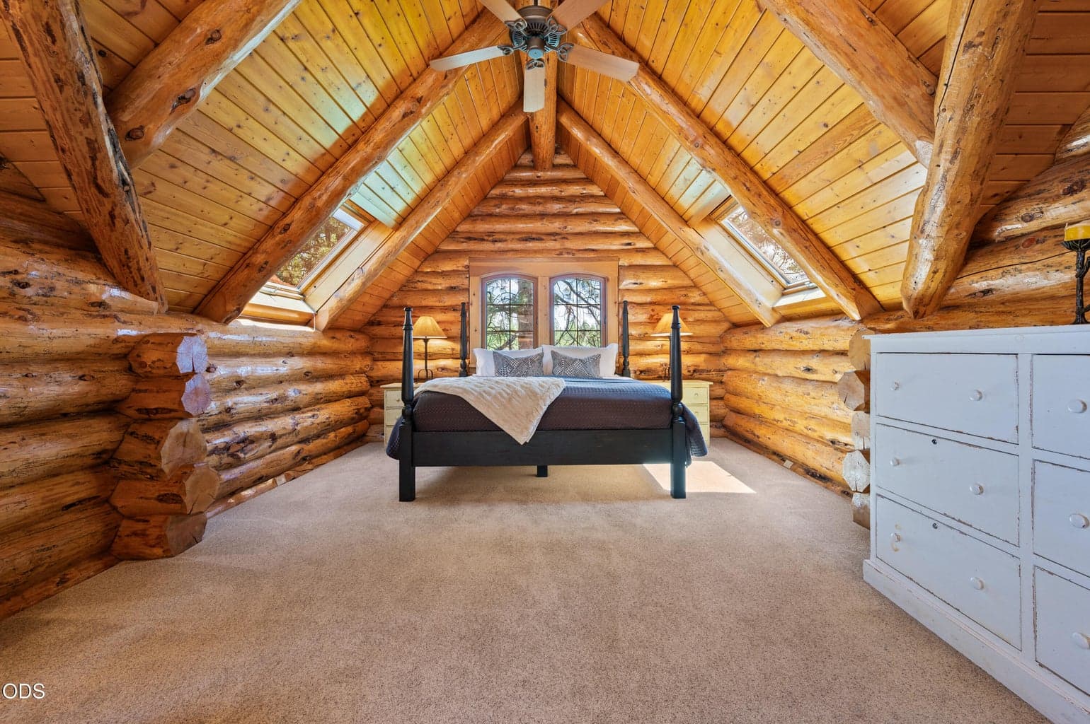 The private upstairs primary suite features soaring vaulted ceilings, exposed log beams, abundant natural light, and beautiful views of the river, creating a warm and inviting retreat.