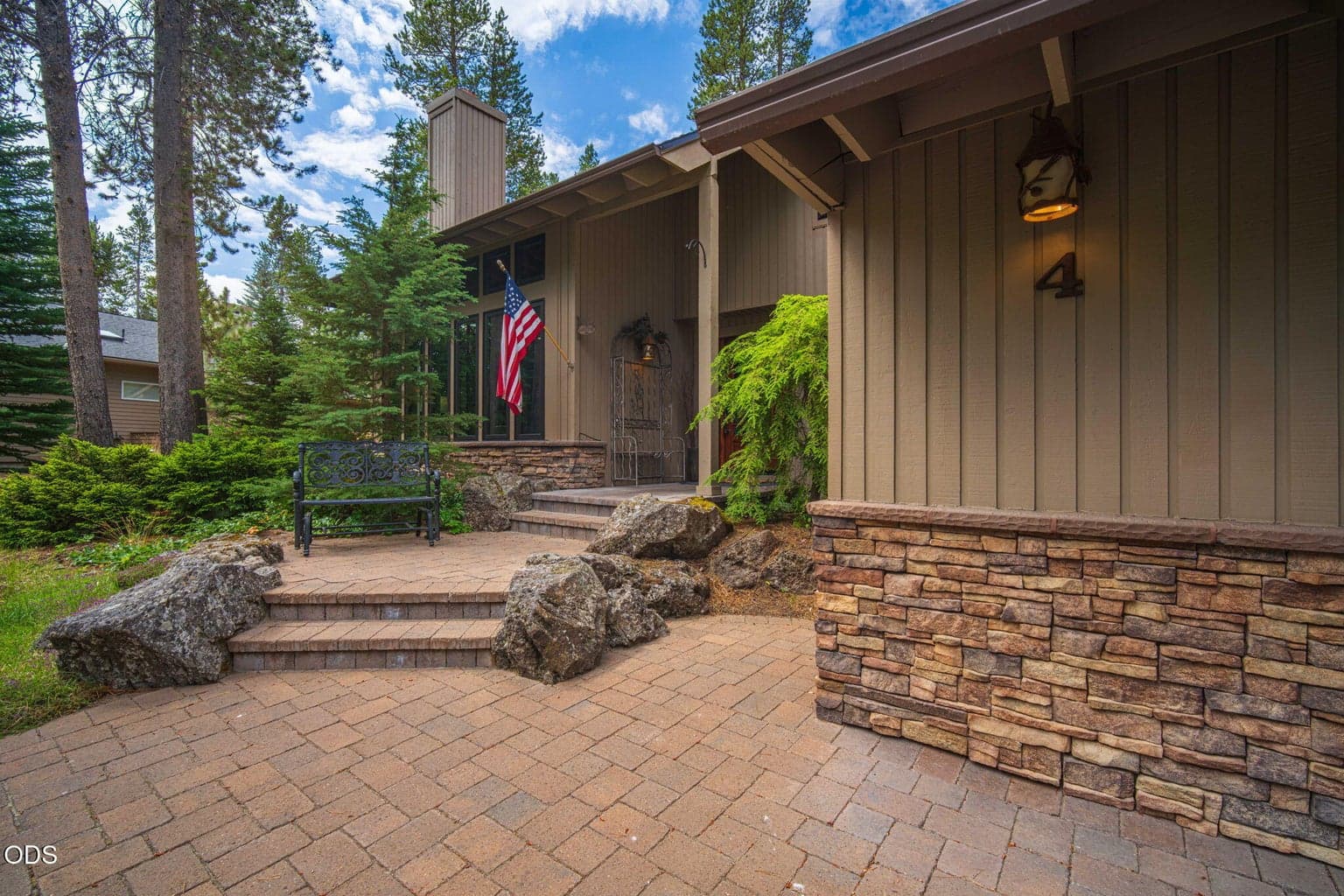 Custom tiered, paver entry steps with inlaid boulders and stacked stone wainscot that adorn the front of the home.