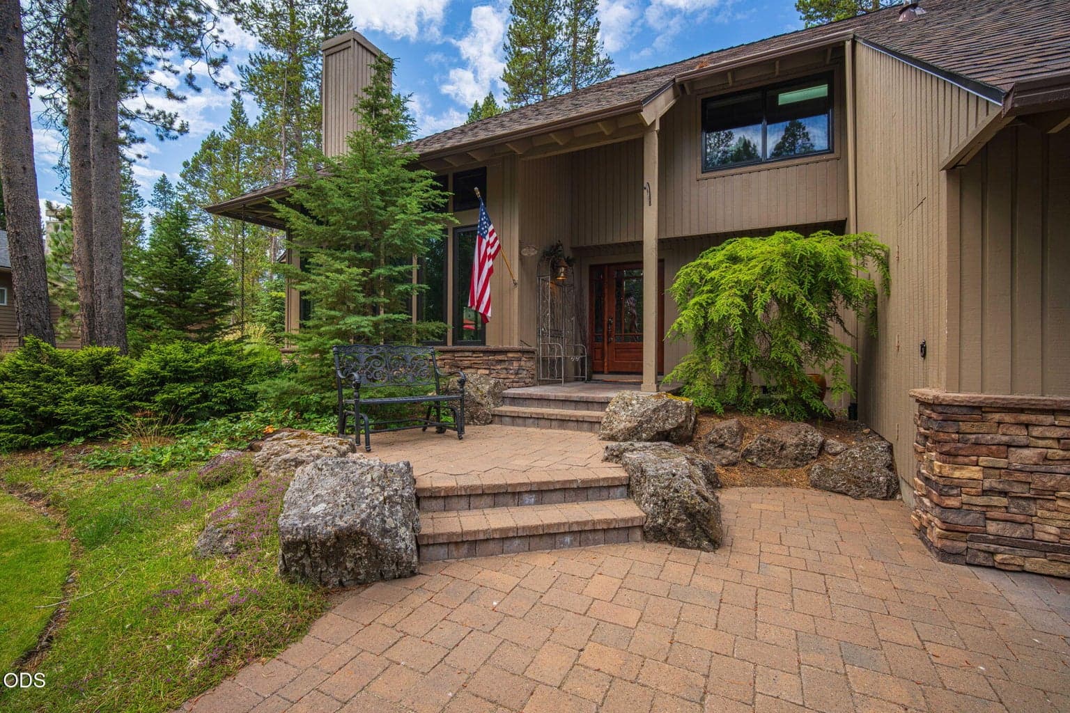 Welcoming front exterior with complementary stone accents, mature landscaping and a paver walkway leading to the front door.