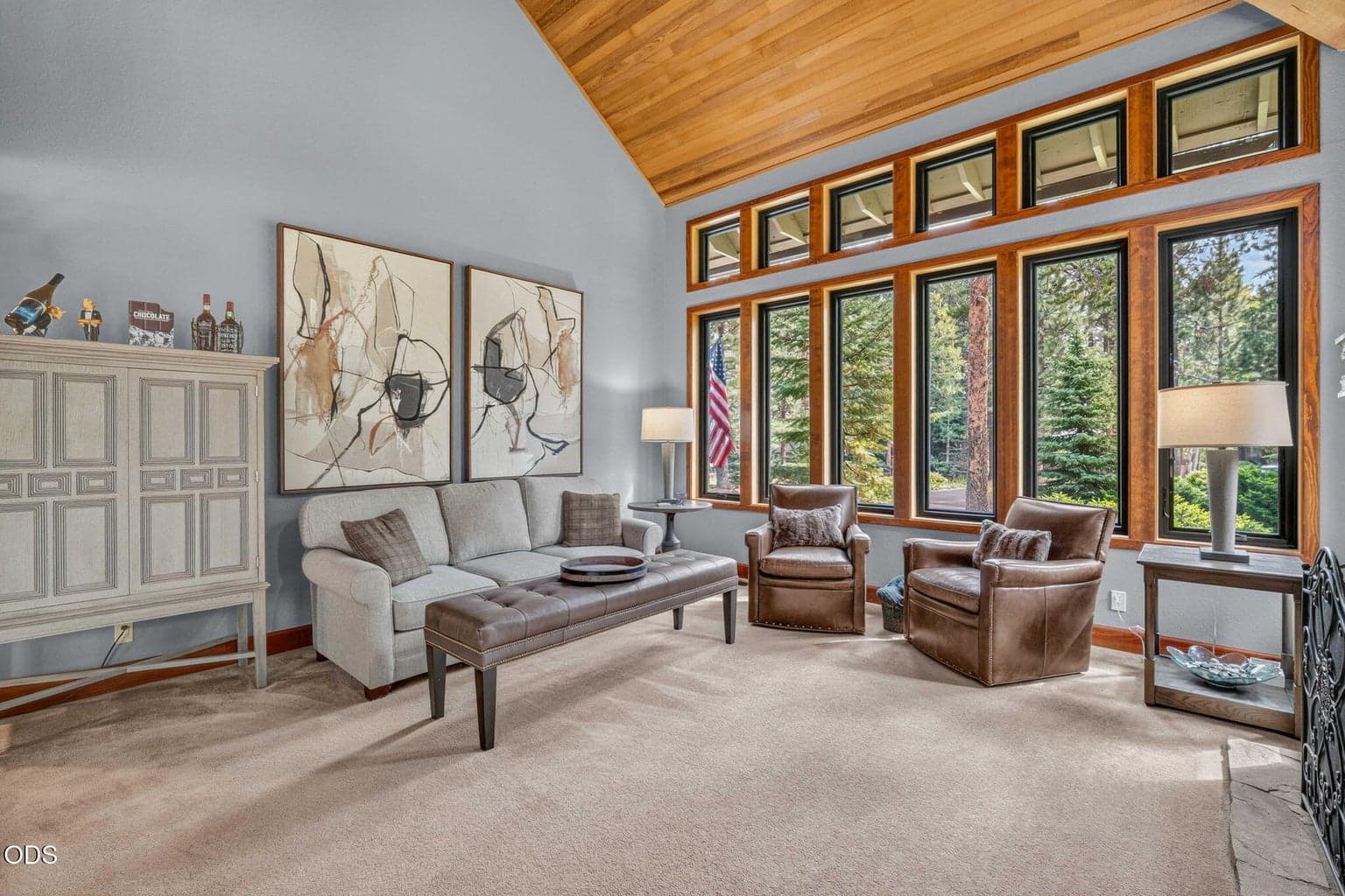Central Oregon sun-filled living space with a calming hue and serene backdrop of mature trees through the windows.