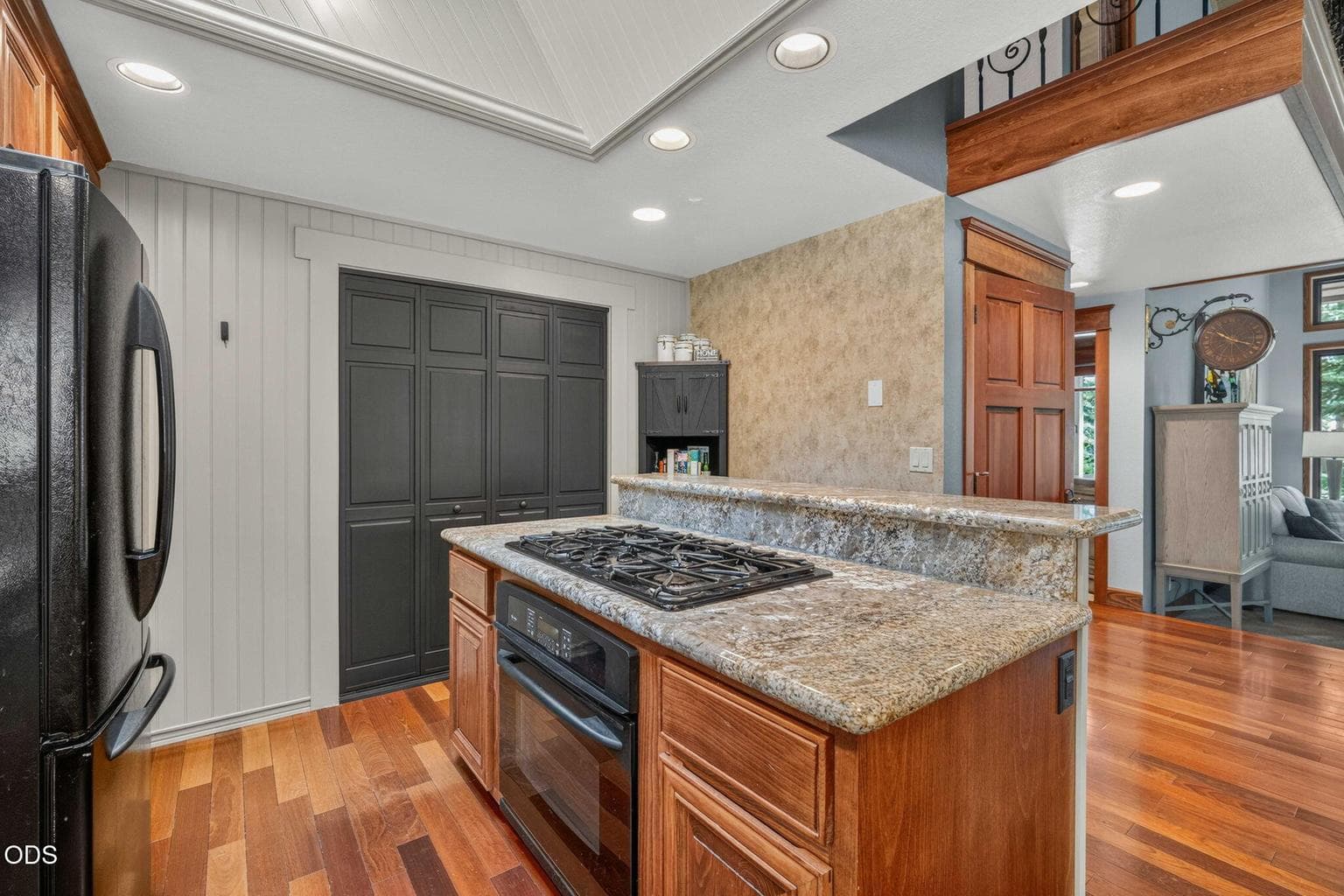 Granite island with gas cooktop anchors this chef’s kitchen with ample storage and style.