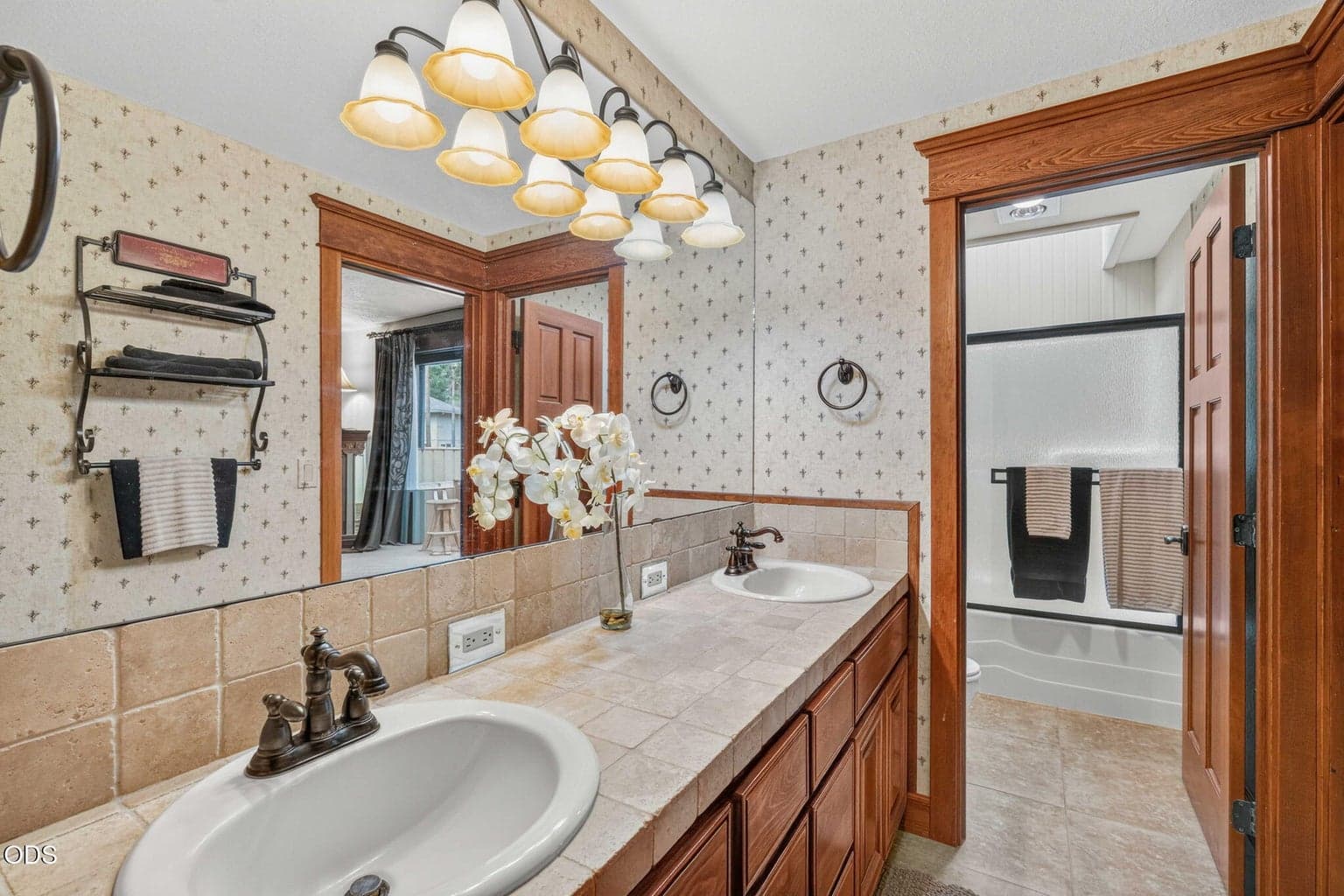 Main level, full bath with dual vanity, warm wood trim; flexible access from suite or hallway.