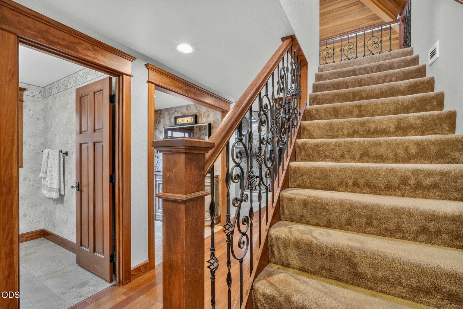 Elegant staircase with wrought iron detail connects main living to upper private bedroom.