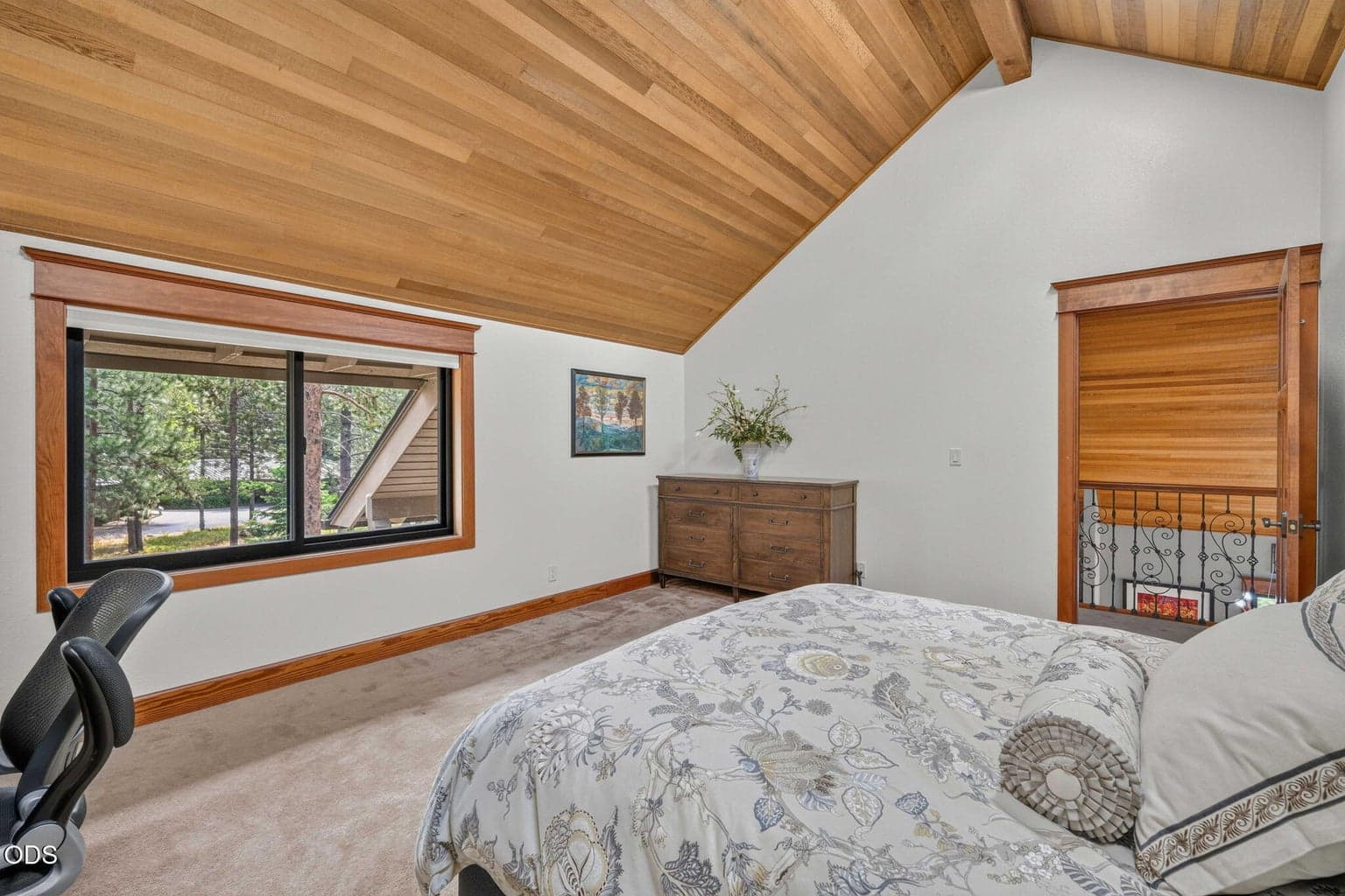 Upper level primary suite, featured here with king bed and tranquil views outside framed by natural wood tones.