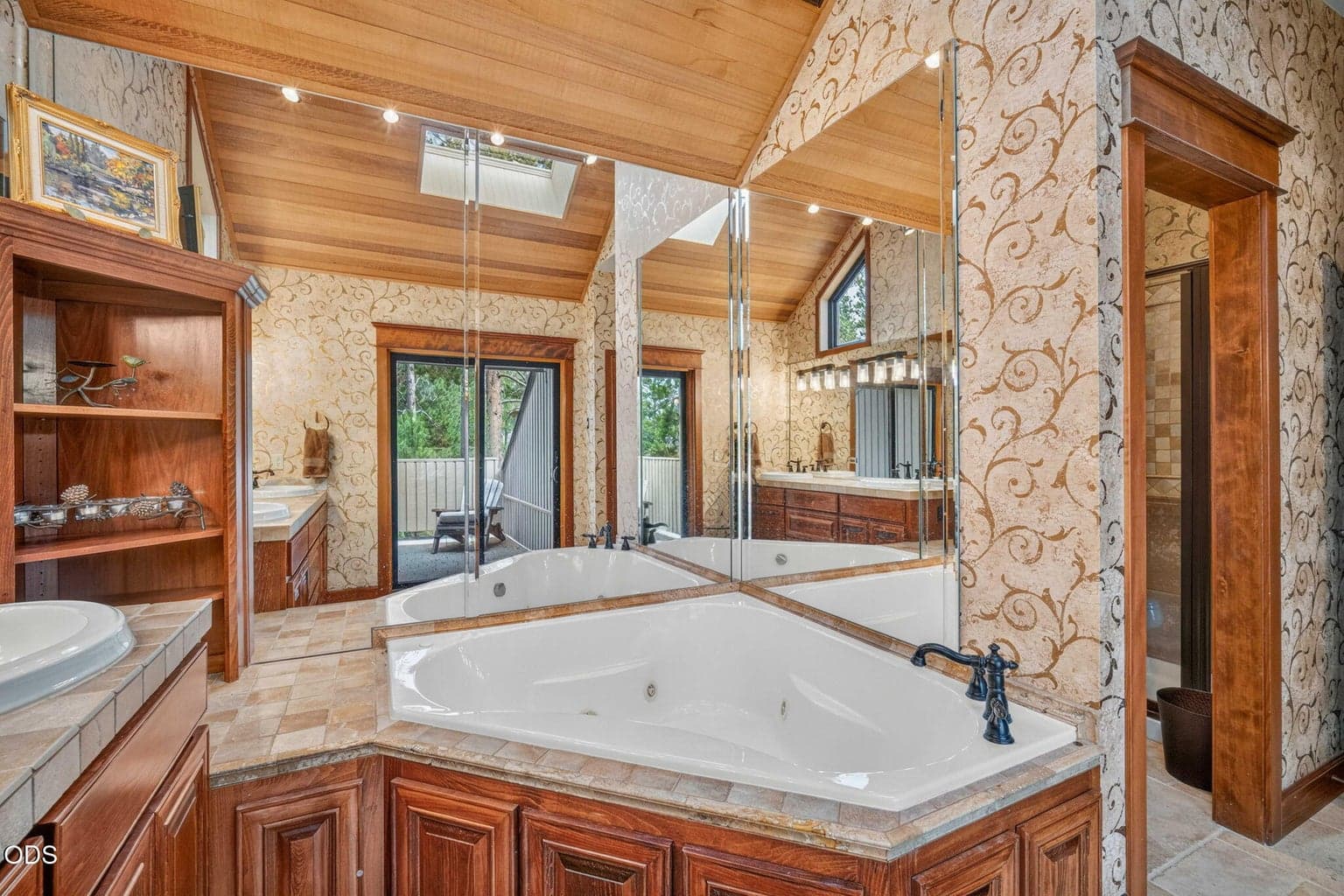 Spa-style jetted tub with mirrored surround and private deck access for morning peace and quiet with nature.