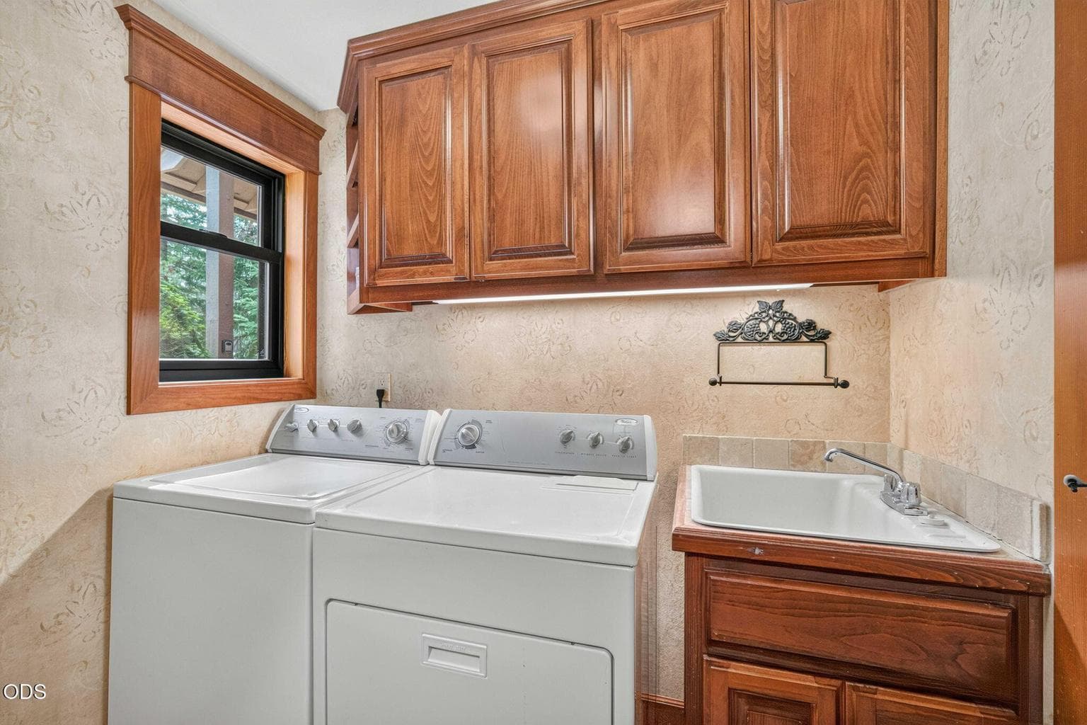 Laundry room with builtin cabinetry, utility sink and window overlooking the pines - bright and functional.