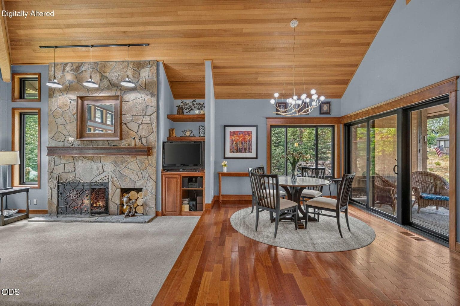 Warm stone fireplace anchors open living and dining with vaulted clear cedar ceilings.