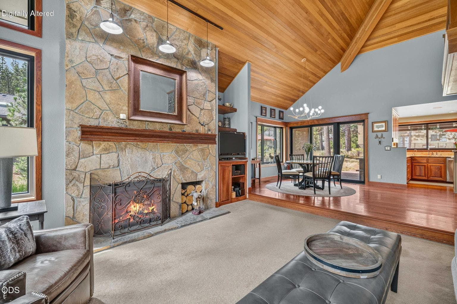 Generous dining space beside floor-to-ceiling stone surround, custom-built mantel and sliding doors to patio.