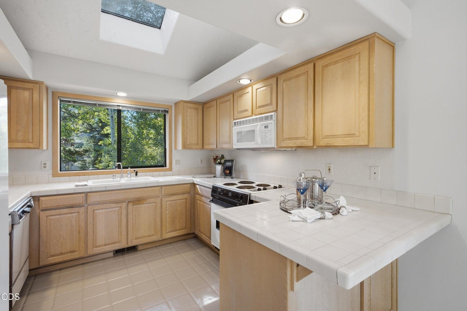Tiled counter & flooring, LOTS of cabinet space w/ quick access to your dining area & upper deck entertaining. A skylight and French doors bring in lots of natural light! Electric range/oven -natural gas is available.