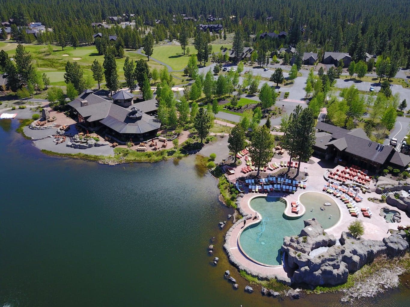 Overlooking snow-capped Mt. Bachelor, the Caldera Springs Lake House & Pool and Fitness Building are the heart of this resort community. The buildings are a wonderful example of rustic “Cascade Heritage” architecture featuring a restaurant, a full array of exercise, fitness, and aquatic facilities. Together these buildings provide the social focus and gathering place for families and friends during their stay at Caldera Springs. The architecture features timber structural elements, expansive ceilings with natural daylighting, copper roofs, and panoramic views to the surrounding landscape and lake. Covered terraces overlook man-made water features that start at the building and wind their way to the lake. Local natural boulders and stone veneer link the buildings to the site and the surrounding volcanic mountains.