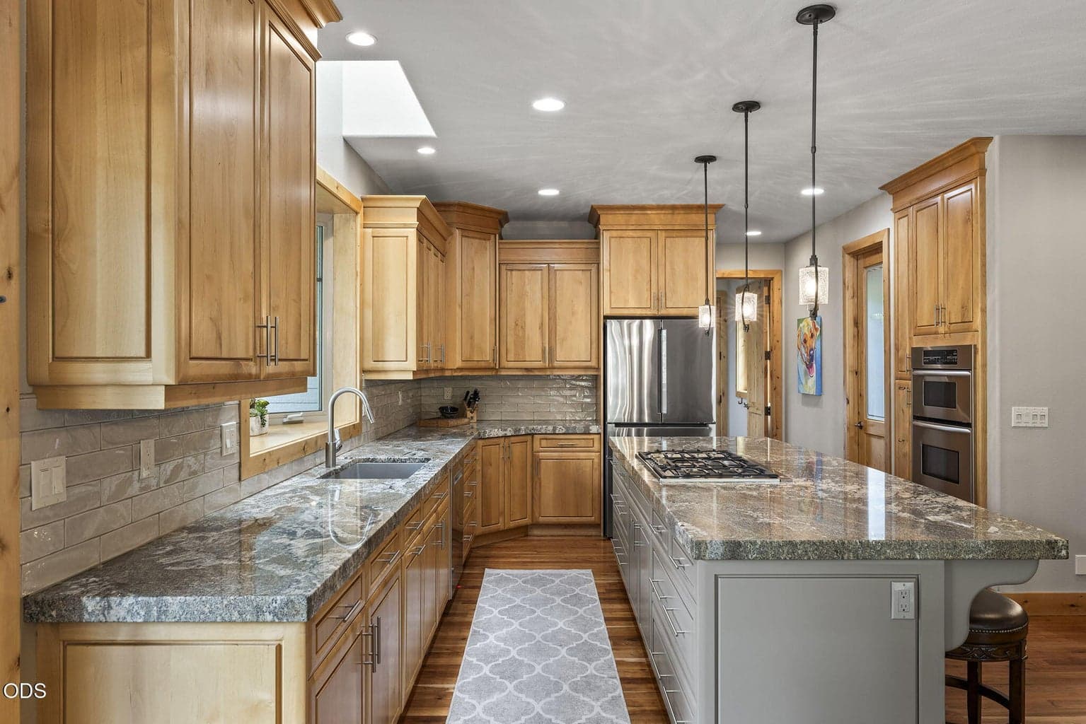 Thermador gas downdraft cook top and updated pendant lighting illuminate the kitchen.