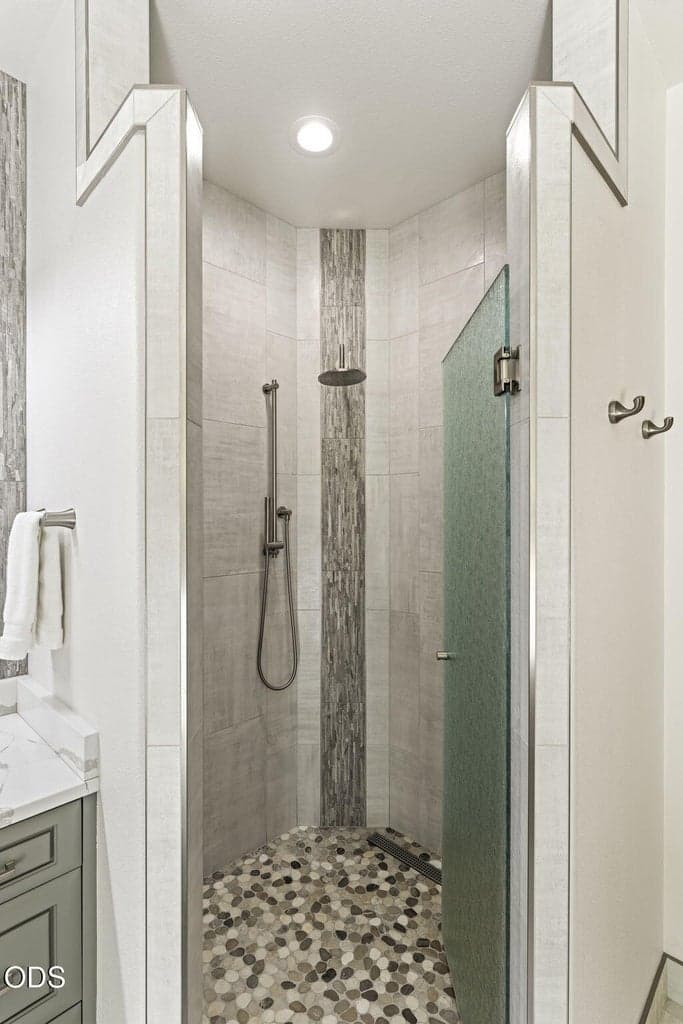 The existing shower reconfigured and surfaced with porcelain wall tile, a rain shower fixture and a 1/2" glass swing door.