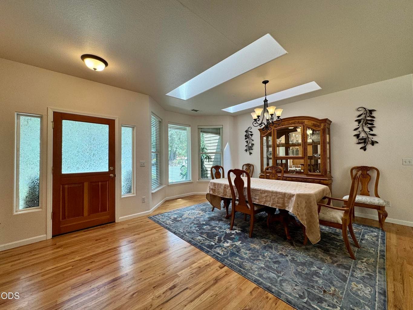 dining on oak flooring and featuring skylights