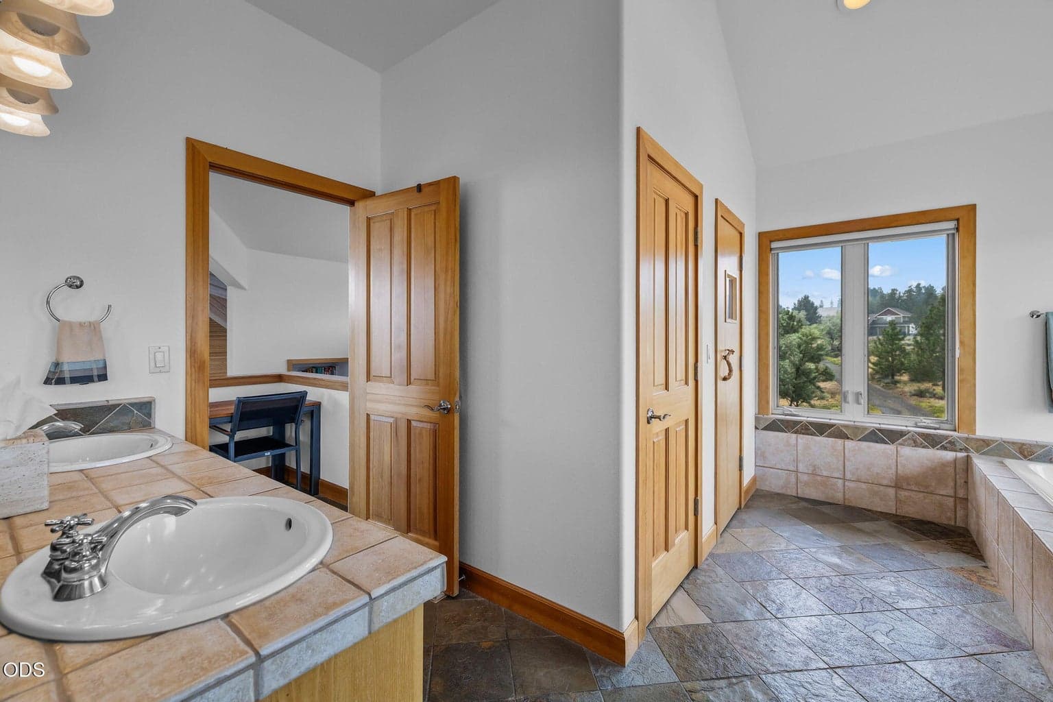 Primary spa-like bathroom with dual vanity, enclosed commode, soaking tub, sauna and large tile shower