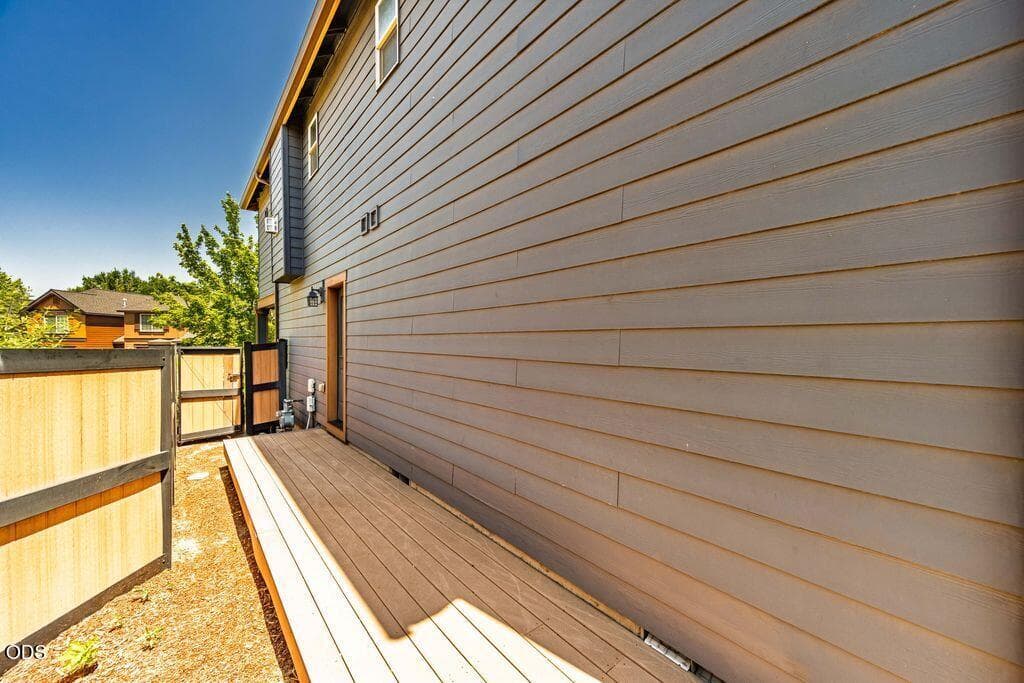West facing deck runs along the side of the home and leads to a grassy area with a paver patio.
