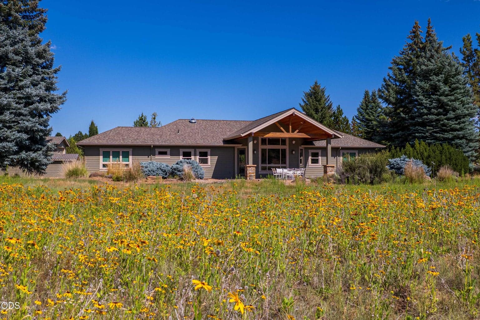 Hero image of home from backyard over cascading view of wildflowers, showcasing vaulted ceiling and roofline