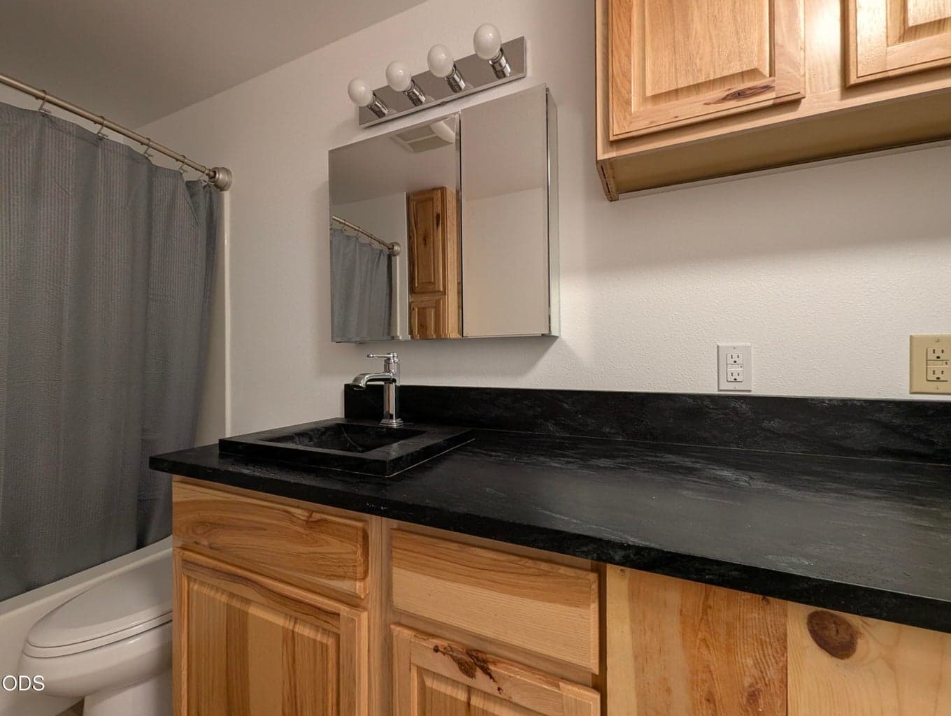 Full bathroom featuring a tub/shower combination, vanity storage, and coordinating finishes.