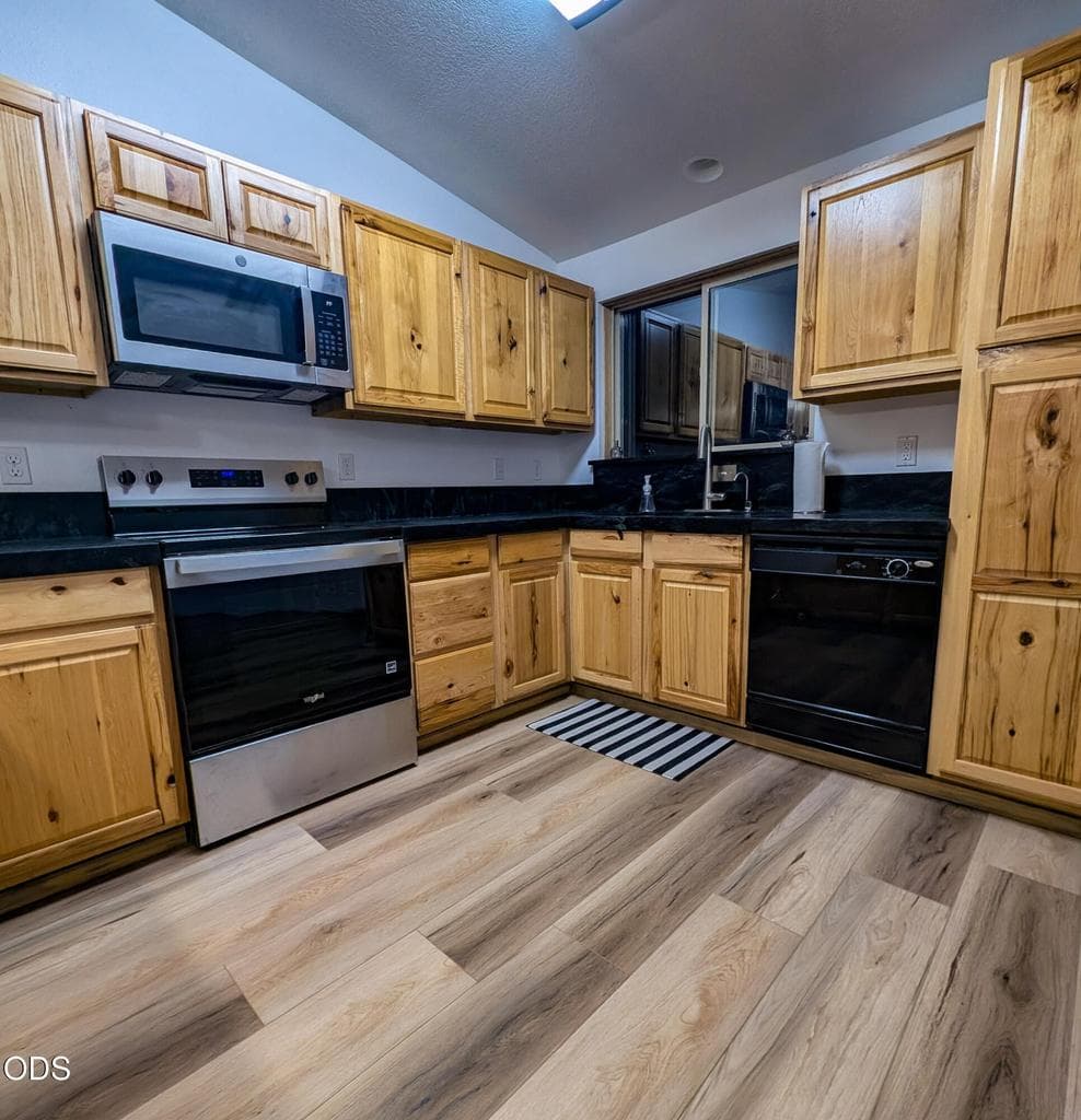 Functional kitchen with wood cabinetry, stainless steel appliances, updated flooring, and ample workspace.