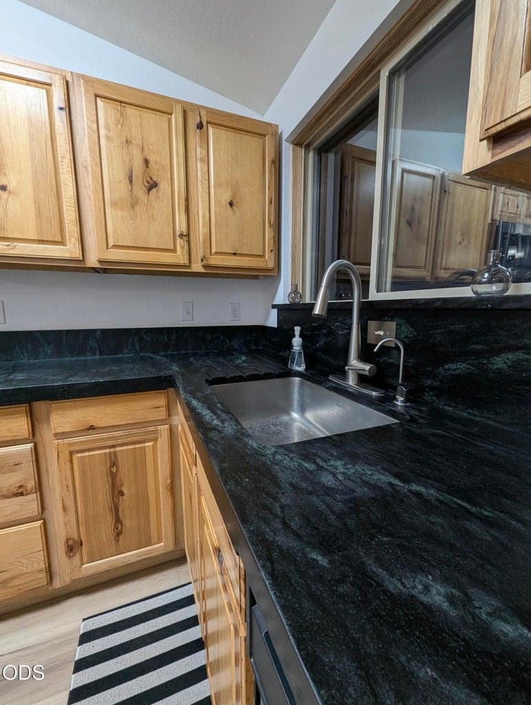 Kitchen view showcasing generous cabinet storage, dark soap stone countertops, and a practical layout for everyday use.