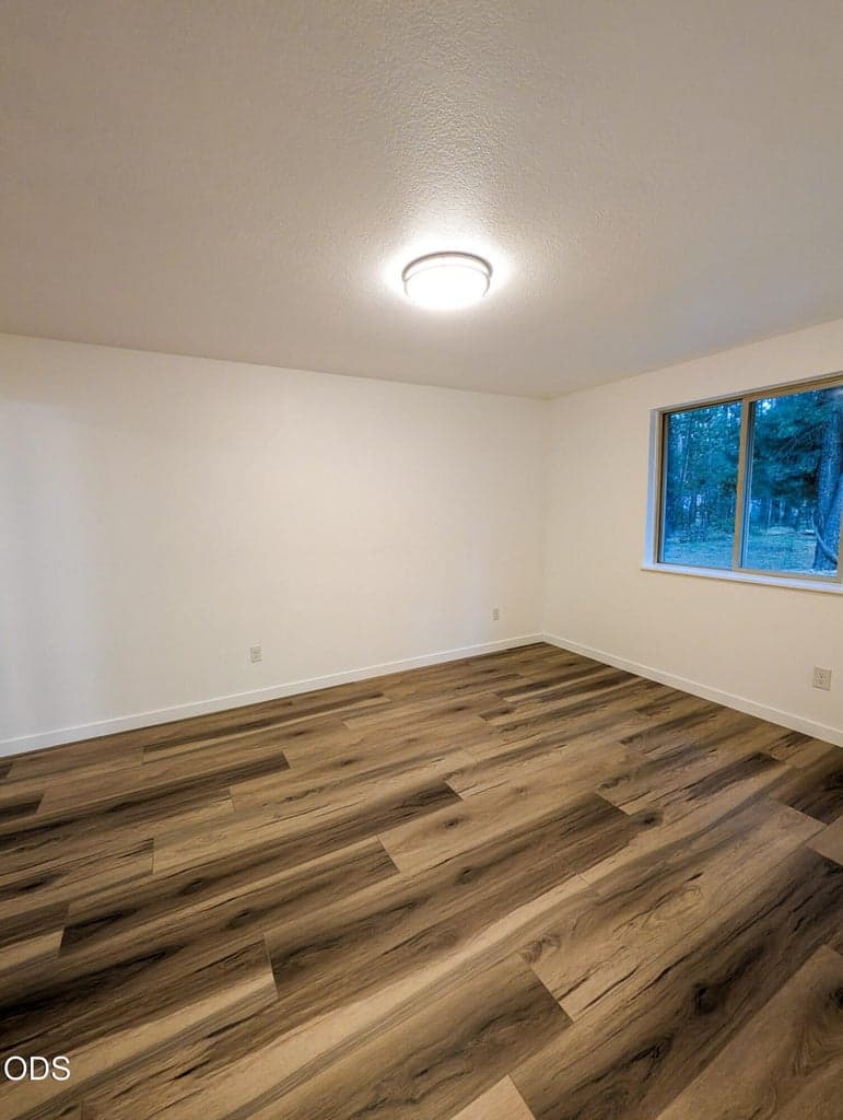 Alternate view of the main bedroom highlighting natural light, updated floors, and a comfortable room layout.