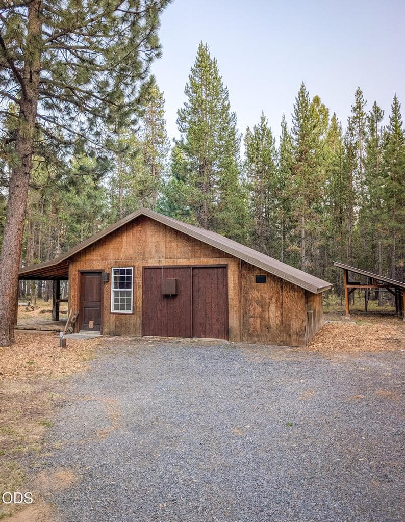 Detached shop with easy driveway access, surrounded by mature trees and a spacious natural setting.
