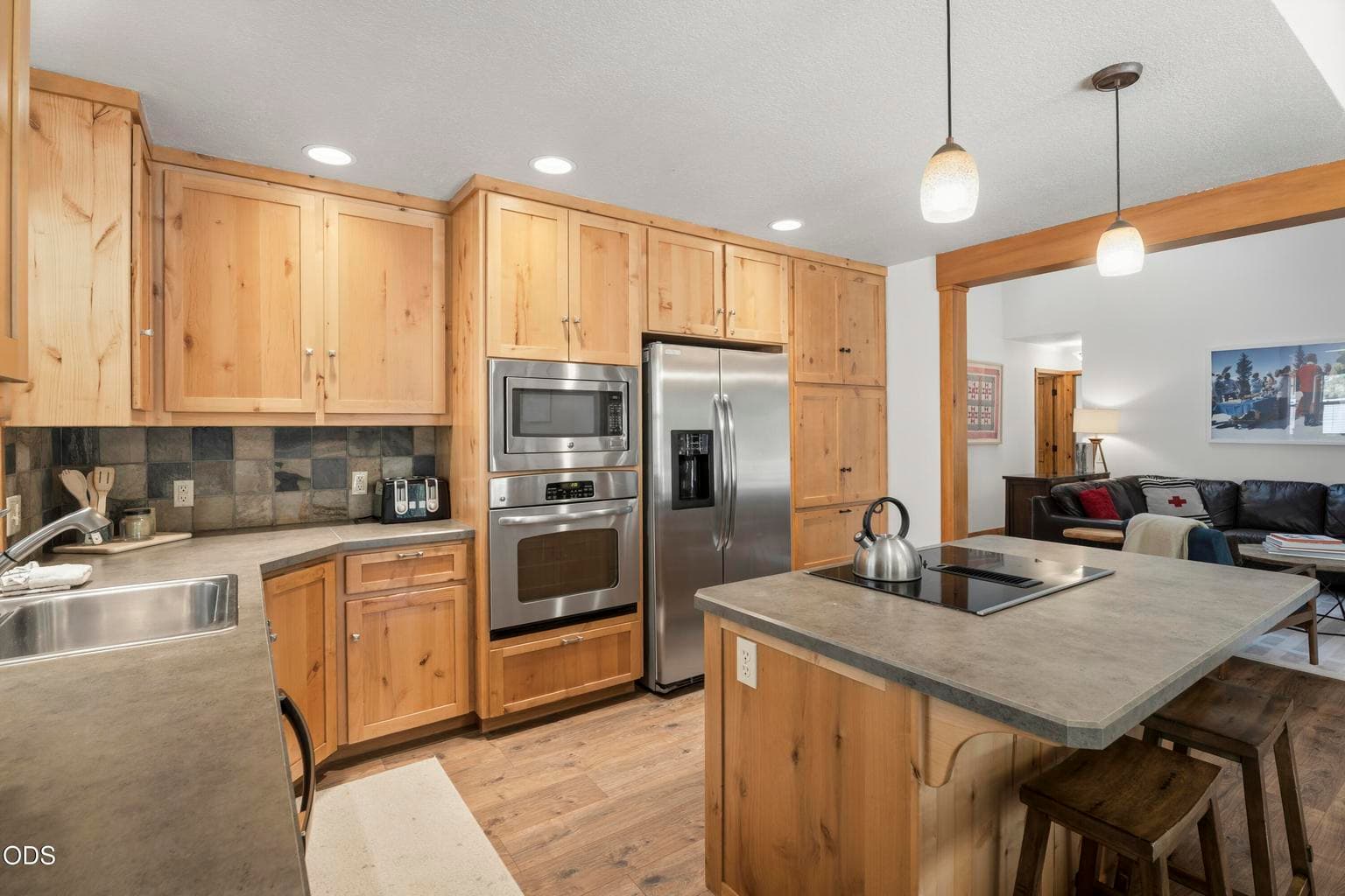 The open kitchen and dining area features knotty wood cabinetry, a center island with seating, and an ideal layout for gathering with family and friends.