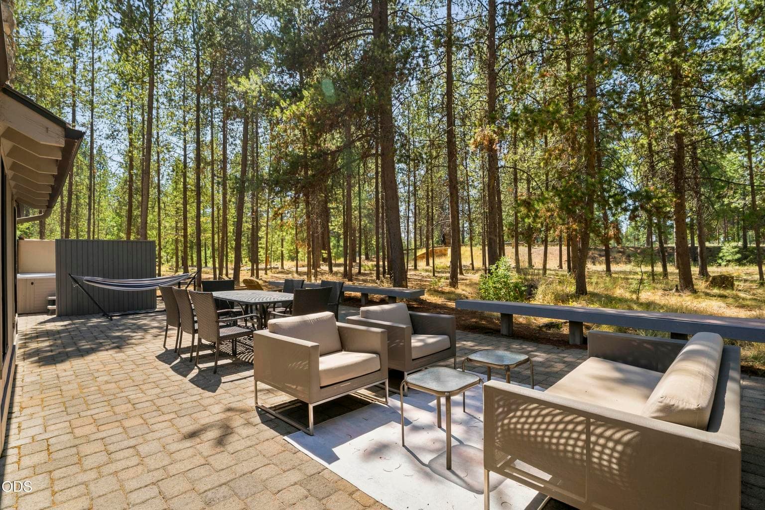Expansive paver patio with hot tub and multiple seating areas offers the perfect setting to relax and entertain among the towering pines.
