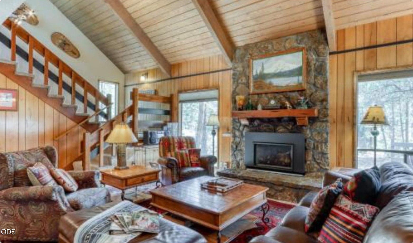 Classic Sunriver living room with vaulted wood ceilings, exposed beams, and a floor-to-ceiling lava rock fireplace as the central gathering space.