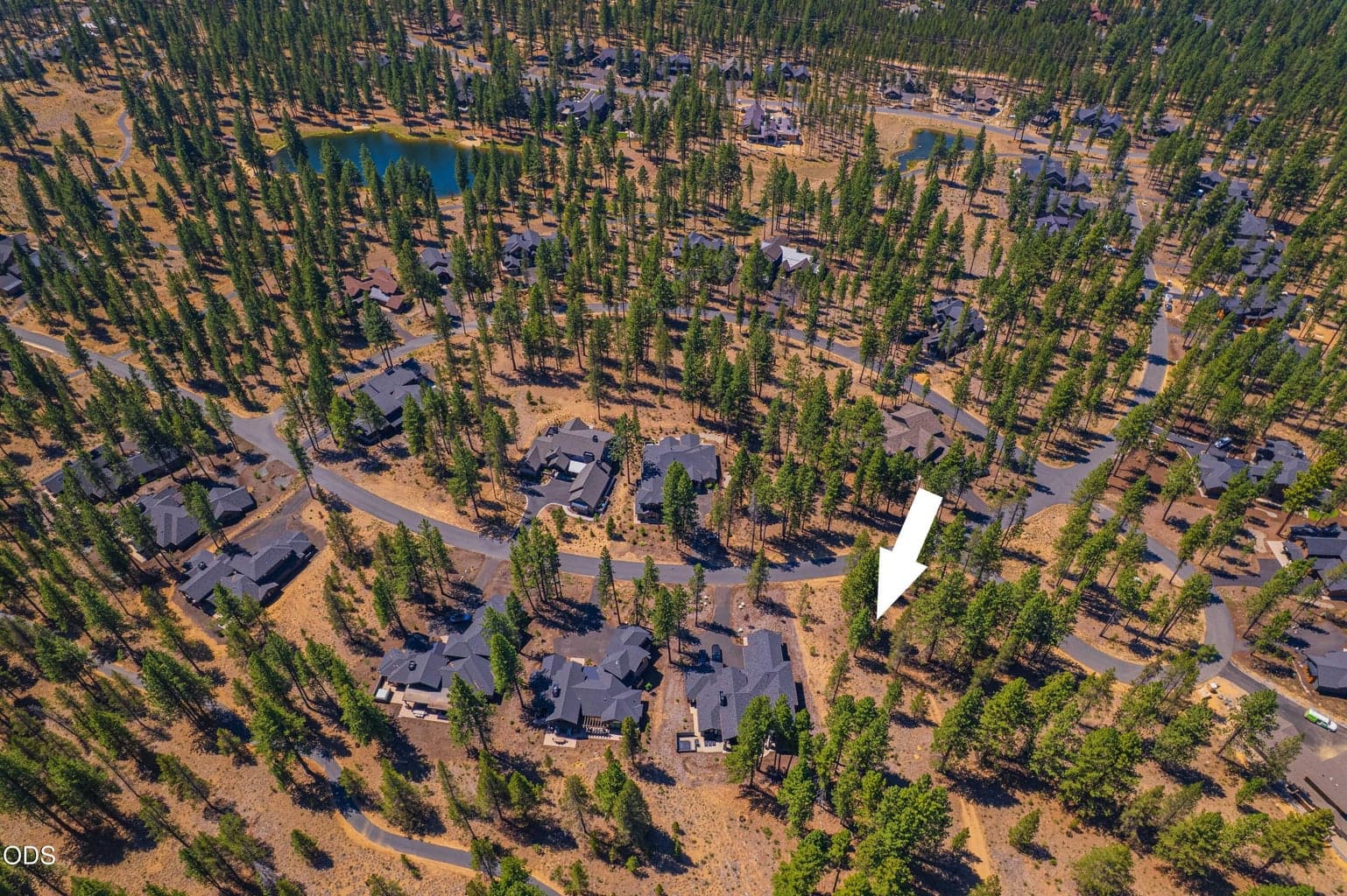 From above, the surrounding neighborhood comes into view, with established homes, forested surroundings and Mirror Lake helping define this Caldera Springs location.