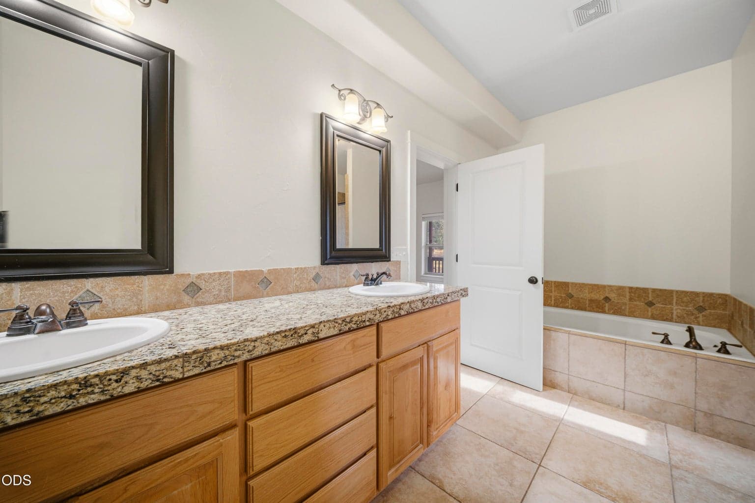 Dual vanity with soaking tub with granite and travertine