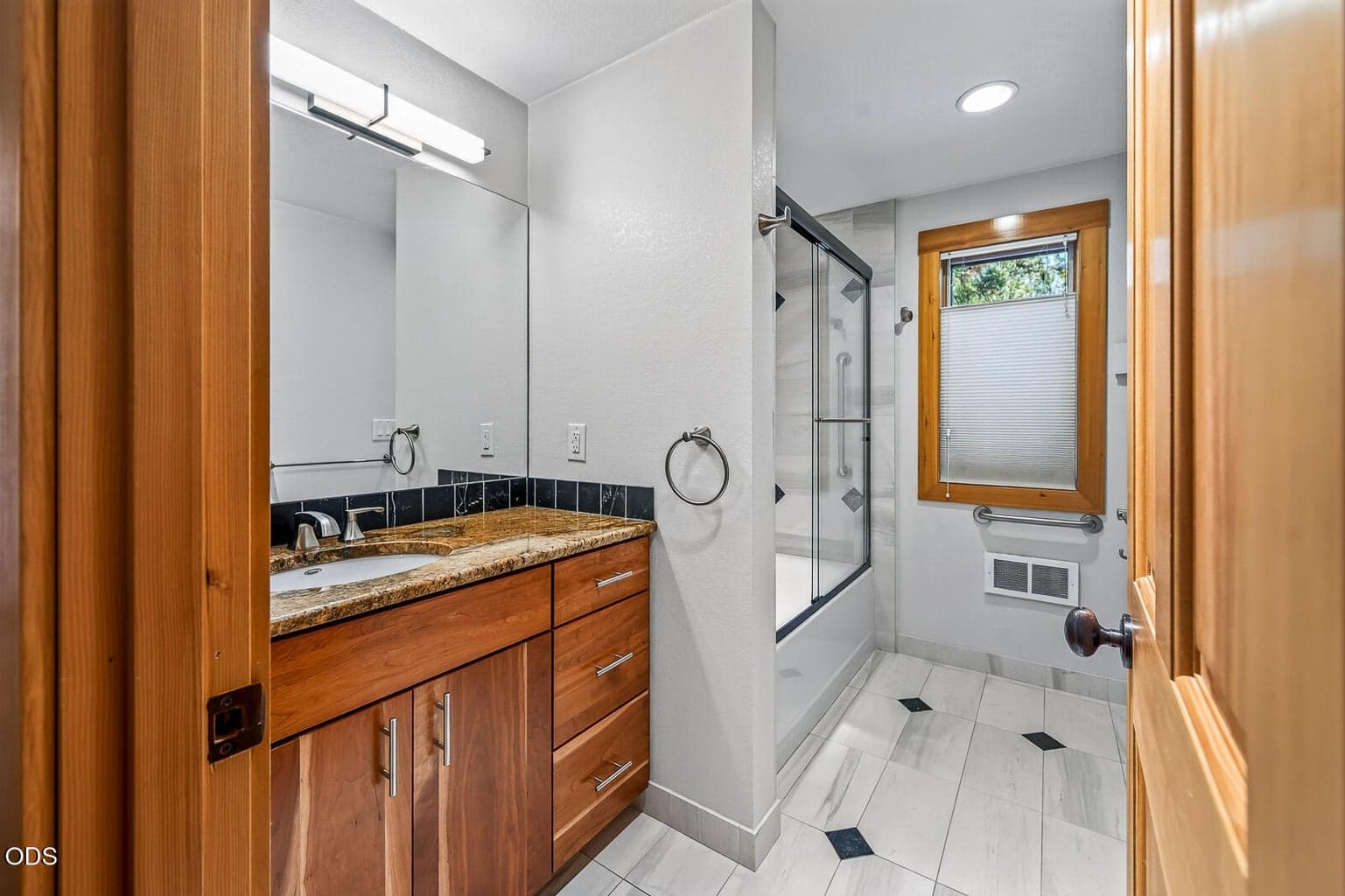 Guest bathroom. Tiled floor and shower, with a granite counter.