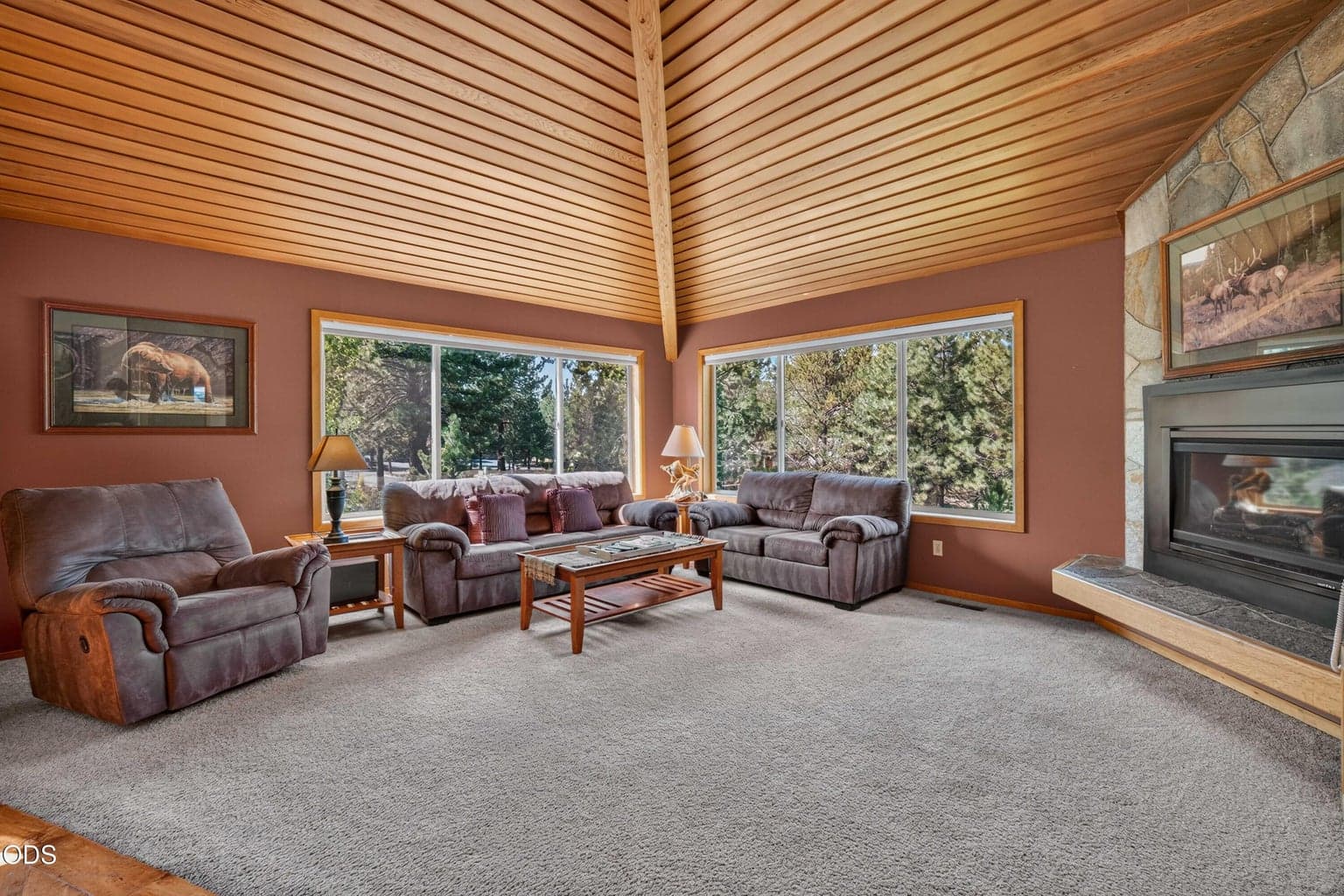 Expansive windows bring the surrounding pines into the living room and fill this comfortable gathering space with natural light.