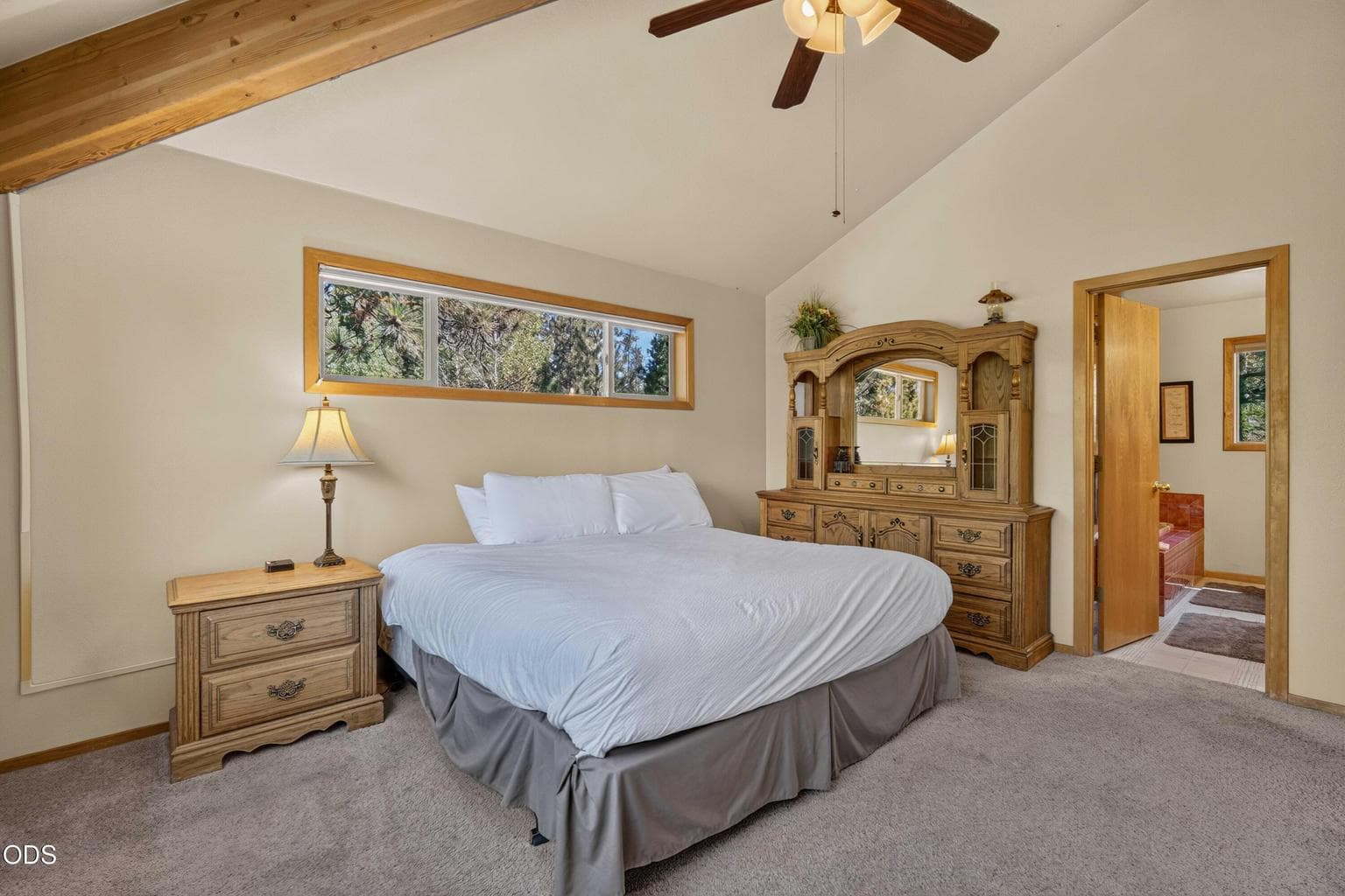 The spacious primary bedroom offers a peaceful retreat with treetop views and vaulted ceilings.