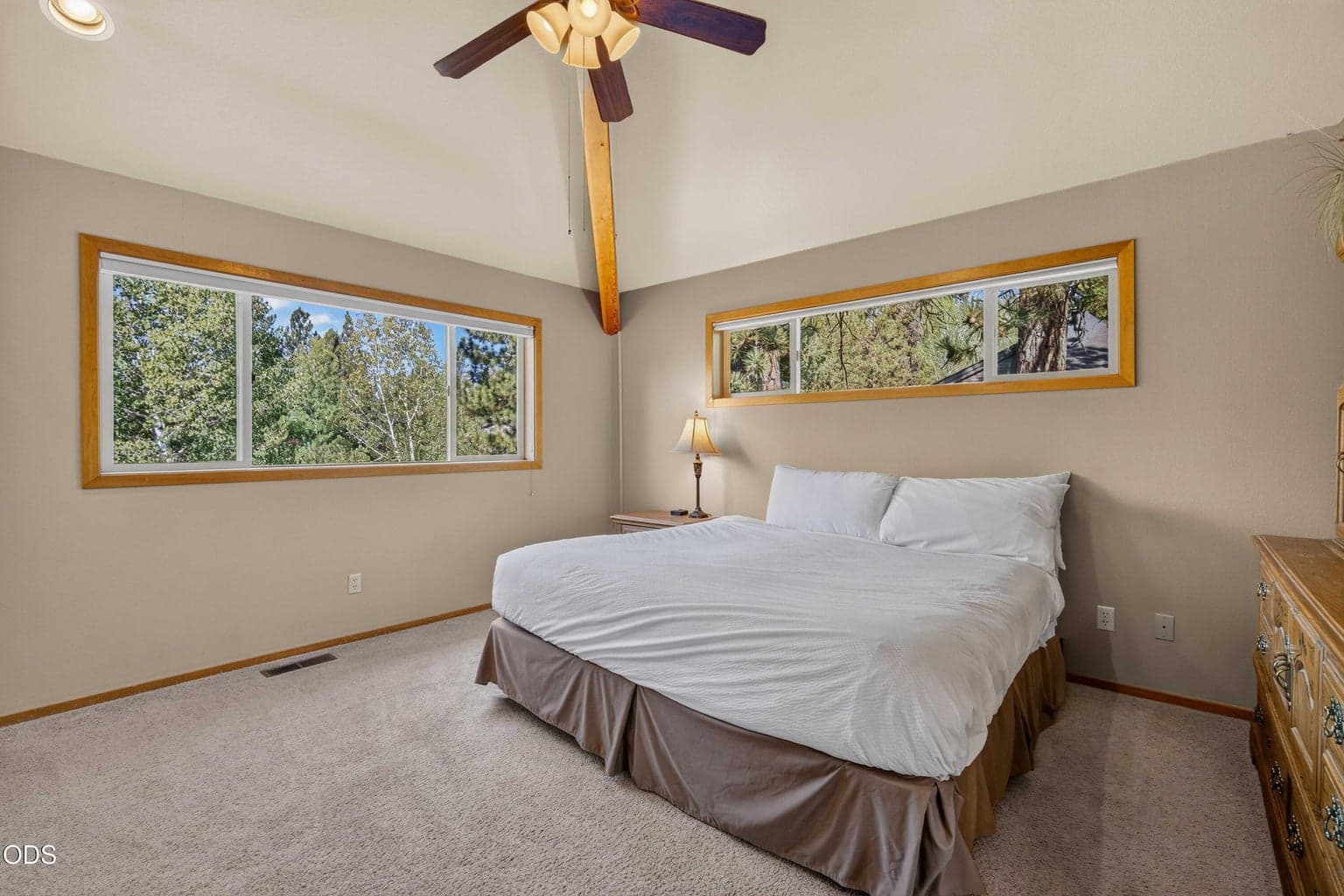 Large windows and soaring ceilings give the primary suite an airy connection to the surrounding forest.