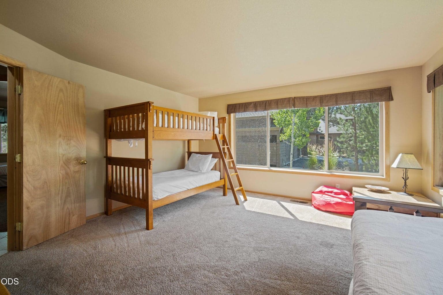 Large windows brighten this versatile bunk room while bringing in views of the surrounding pines.