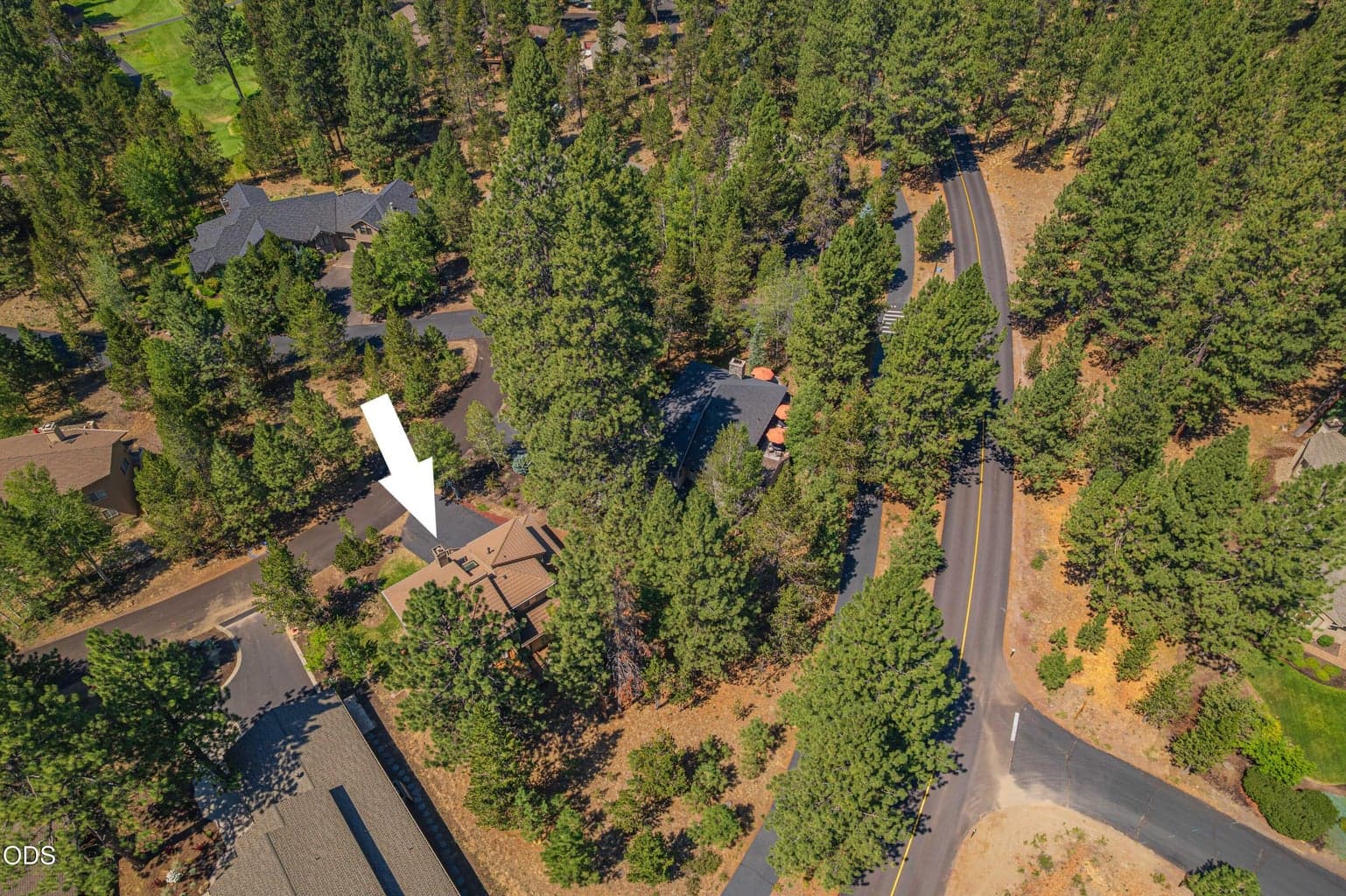 An aerial view highlights the home’s wooded Sunriver setting and its position along East Cascade Road, surrounded by the natural beauty and established character of the community.
