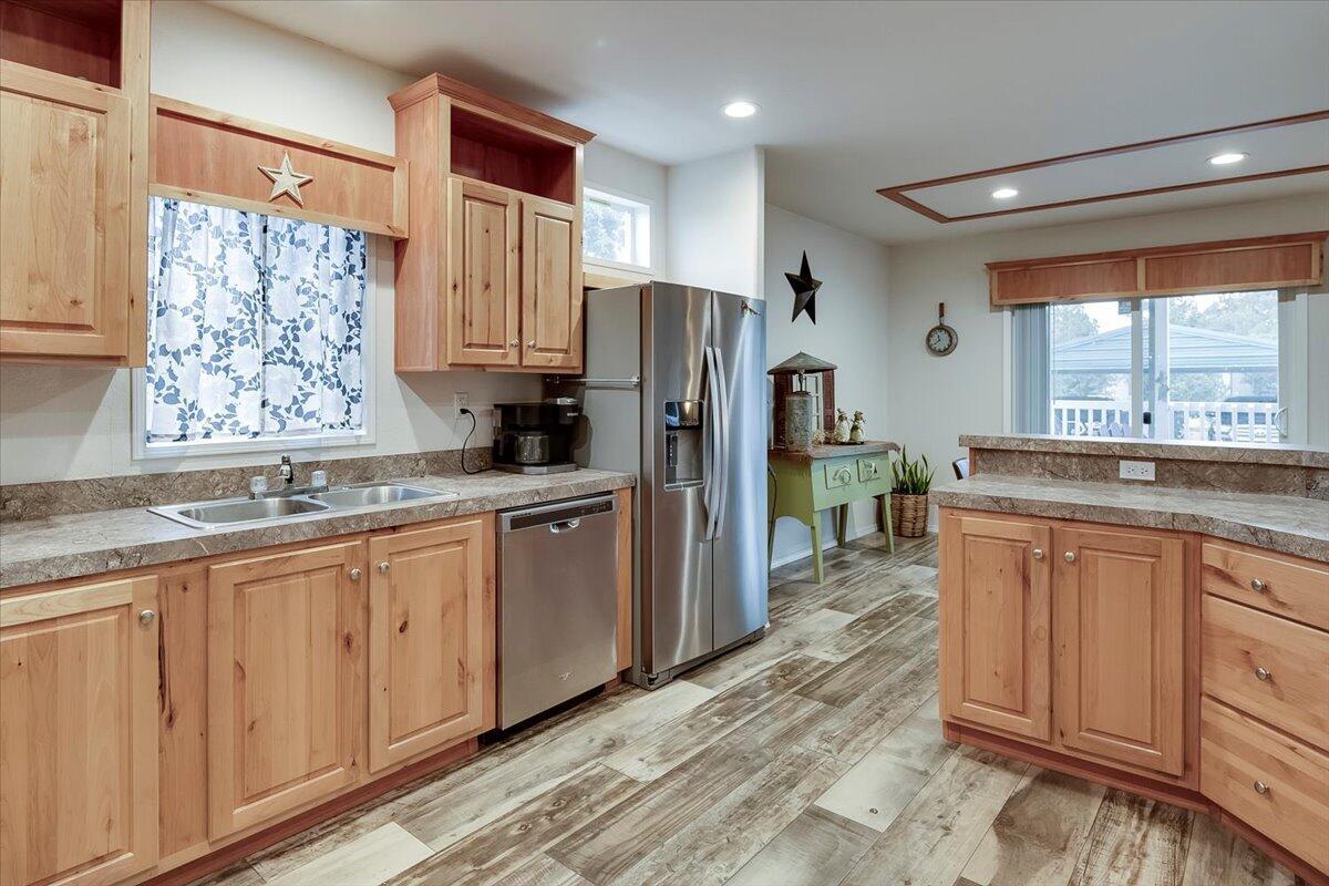 Kitchen with solid counter tops, wood cabinets and stainless steel fridge and dishwasher