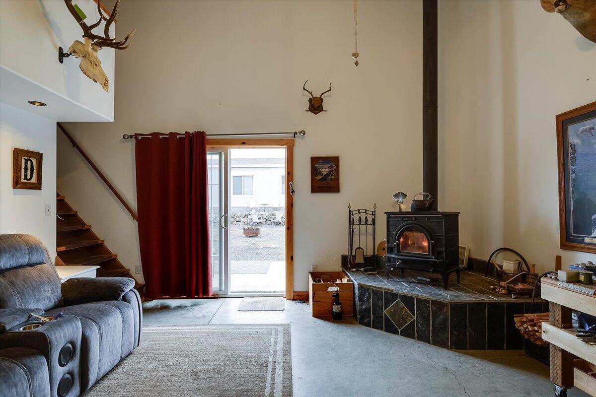 Living room in shop with wood stove, sliding glass doors, stairs to sleeping and/or work loft area