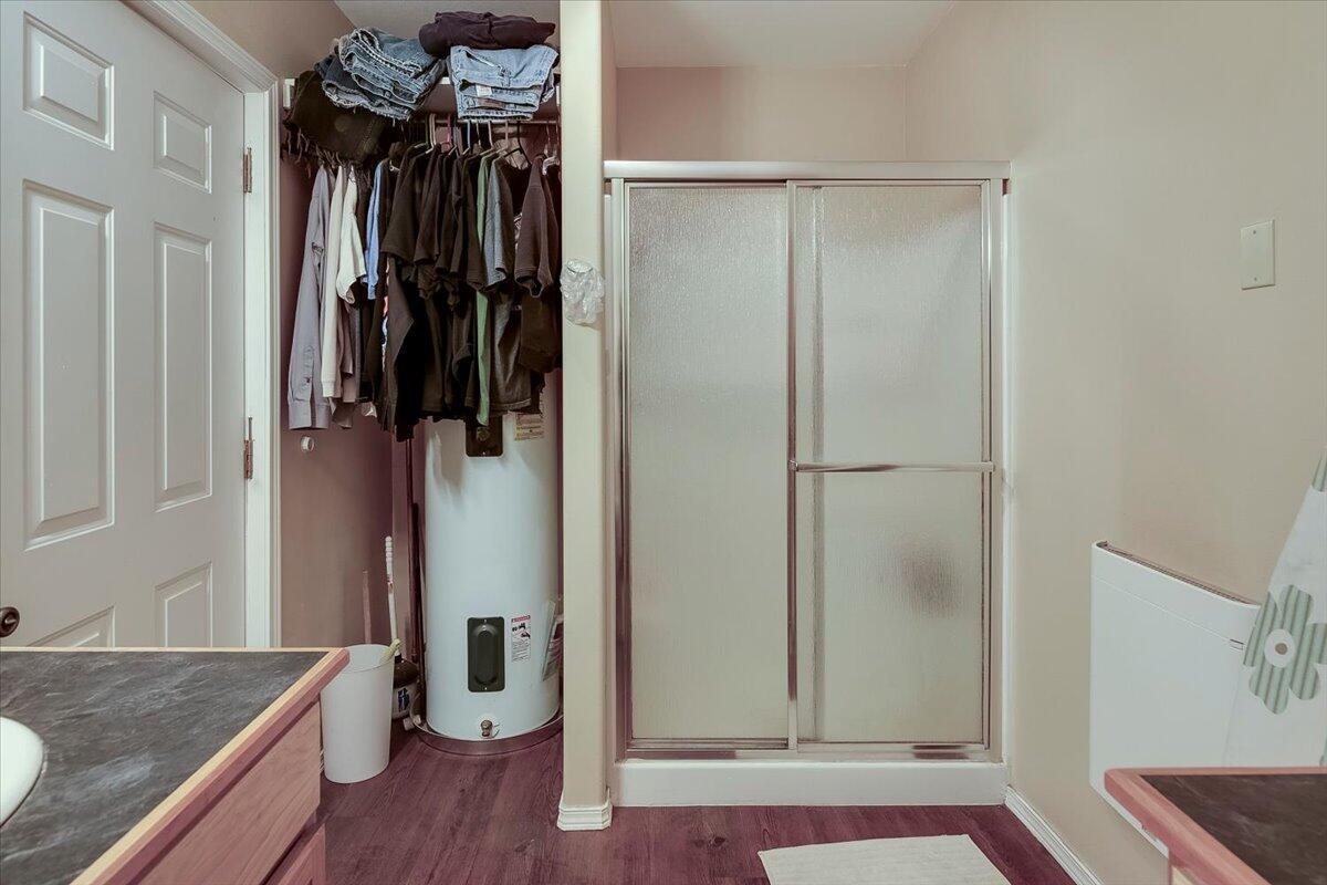 Bathroom in shop with fiberglass shower stall and water heater.