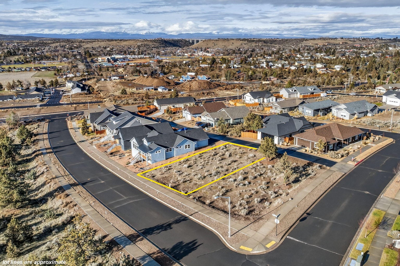 Distant view of surrounding homes and mountain vistas beyond the lot.