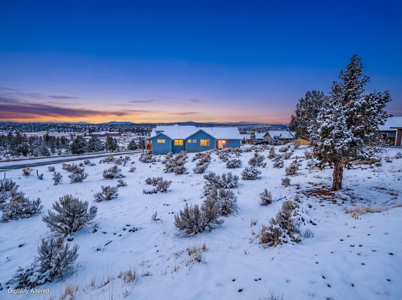 Wide-angle shot of a snow-covered high-desert property at sunset.