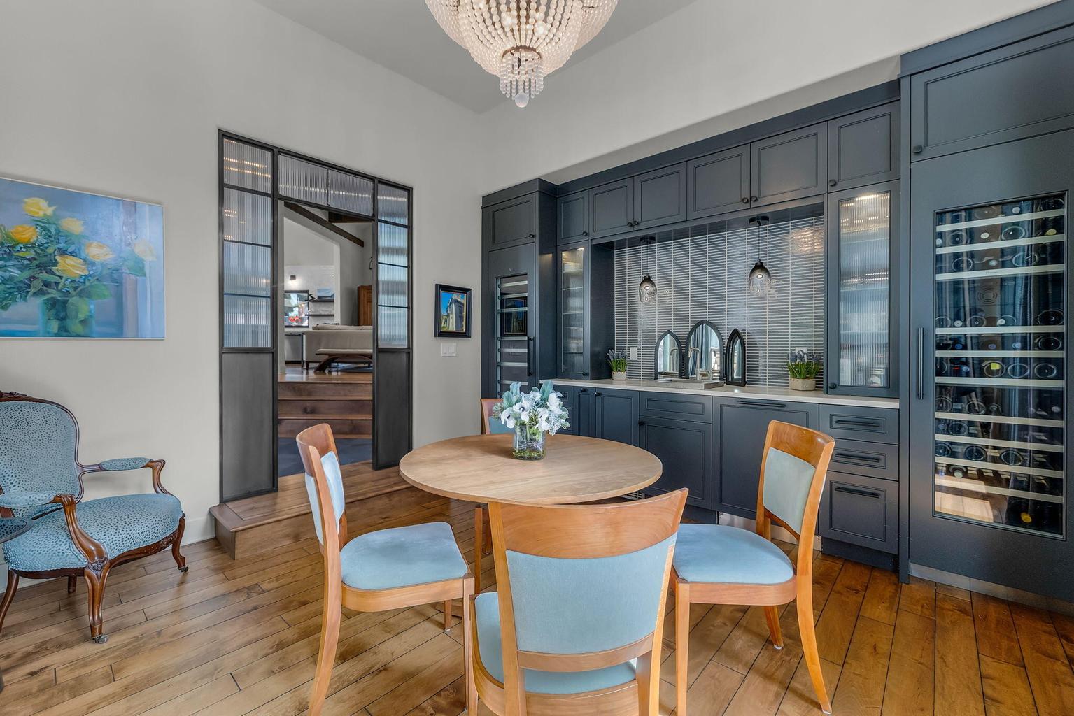 Refined wine and game room just off the entry, featuring custom built-ins with integrated wine storage, hickory hardwood floors, and steel and glass doors that add both style and separation.