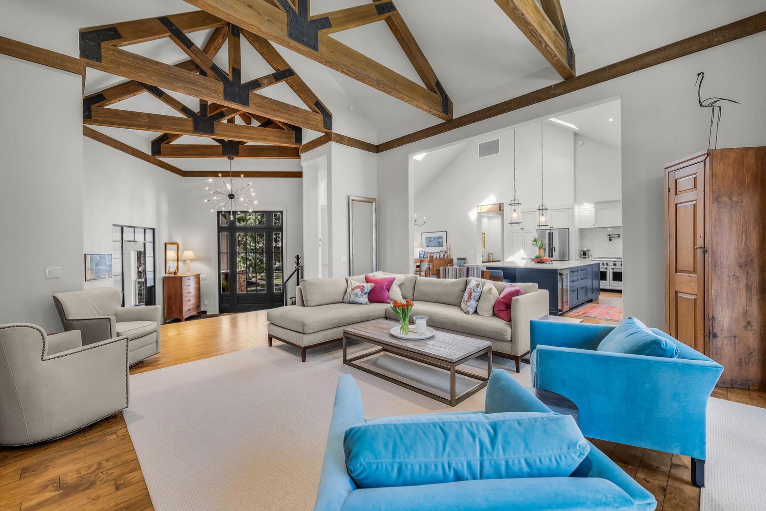 Dramatic great room with soaring ceilings, exposed timber trusses, and a striking stone fireplace, creating a warm and inviting gathering space.