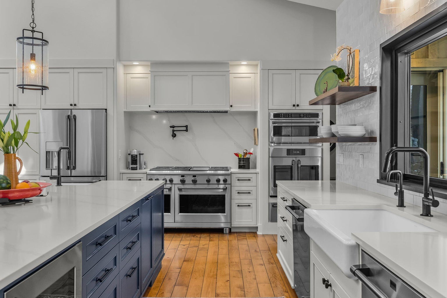 Custom cabinetry, quartz surfaces, and a professional-grade range with double ovens, complemented by integrated refrigeration, farmhouse sink, and designer lighting.