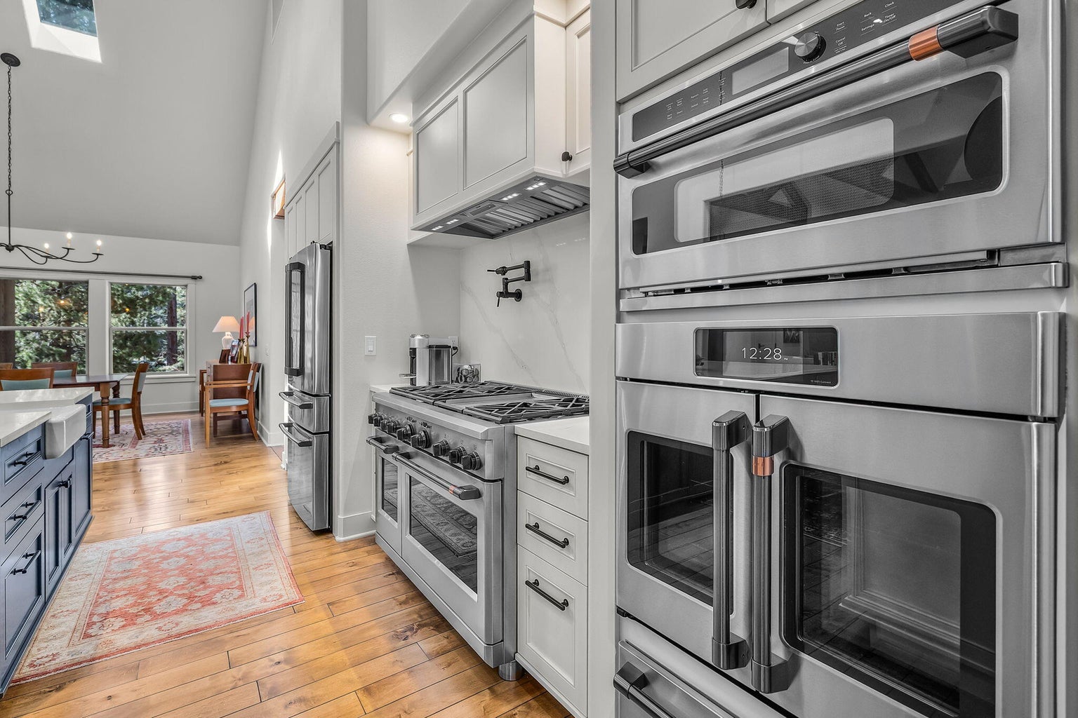 Professional-grade range with custom hood, detailed tile backsplash, and thoughtfully designed prep space with abundant cabinetry and built-in storage.